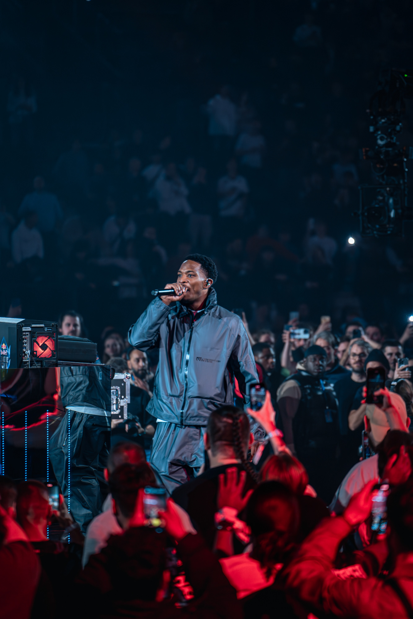 Artiste rappeur en tenue grise performant sur scène avec un micro devant une foule de spectateurs lors d'un événement esport à l'Accor Arena.