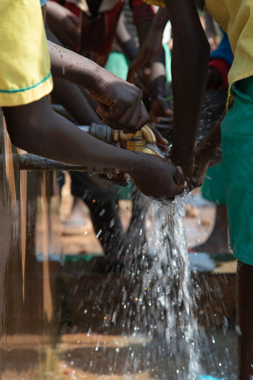 During a break, students from Tulajiji Primary School within Bidibidi Refugee Settlement drink from a public well.