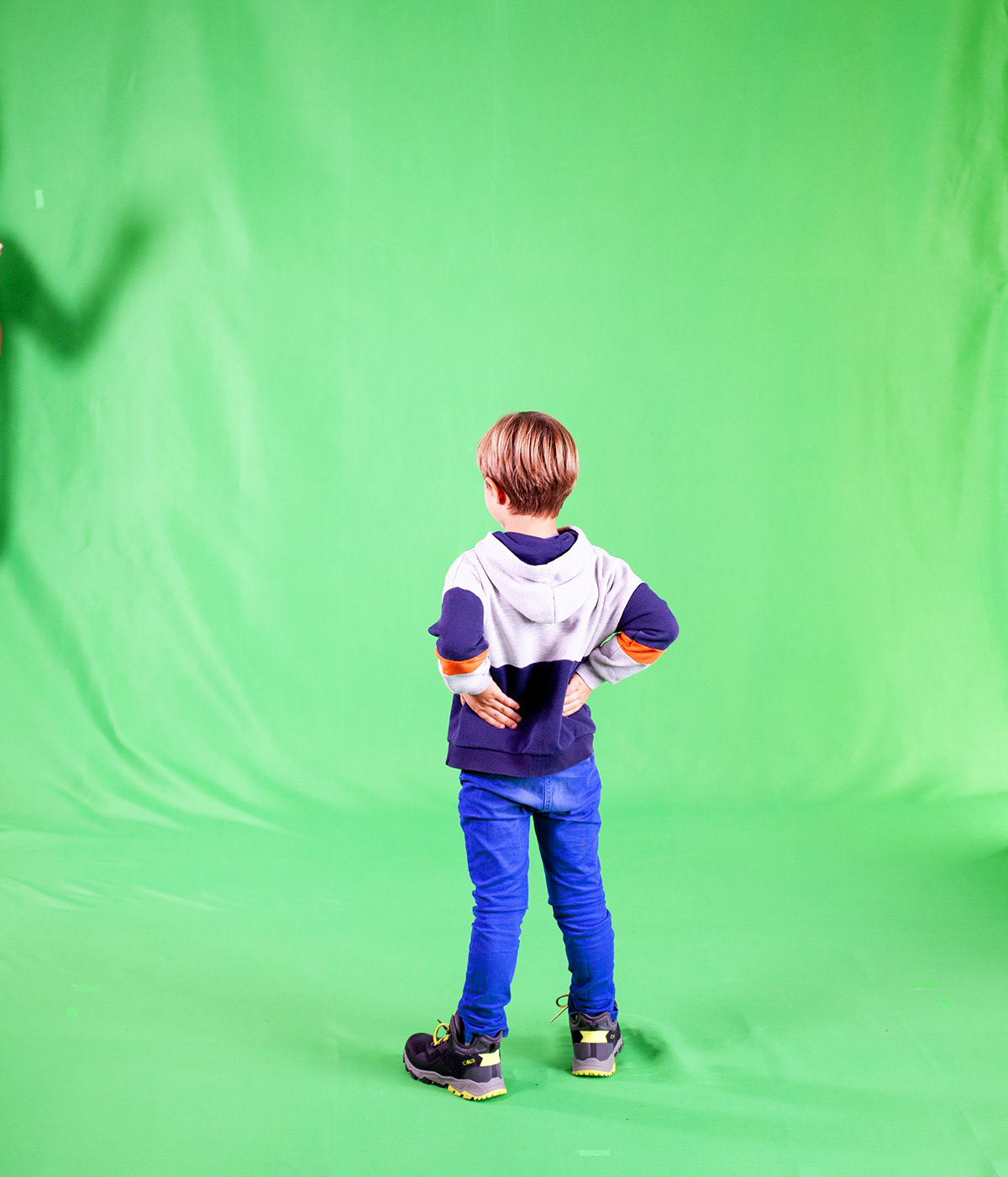 Photo of a kid in gren Croma set., with the hands in his back whearing jeans and sweather. Produced by motion Graphics in Germany. Cast for TV Xmans IDS. Video Production and After Effects animation in Munich. Photography by Rob Adalierd - Aitor Benavent producer