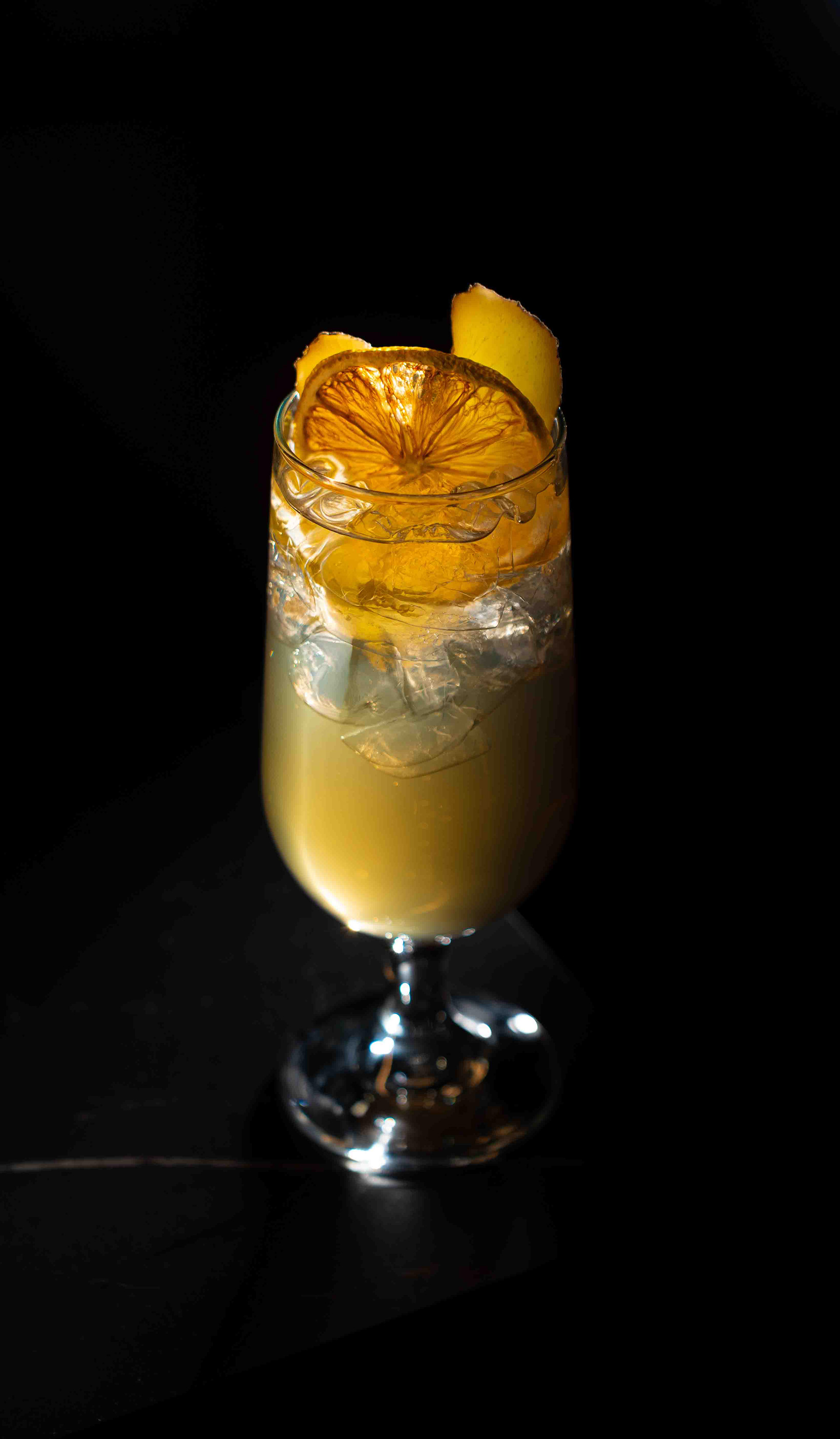 Refreshing citrus cocktail with a dried orange wheel garnish and ice, high-end beverage photography captured by a Toronto-based food photographer for commercial hospitality menus.