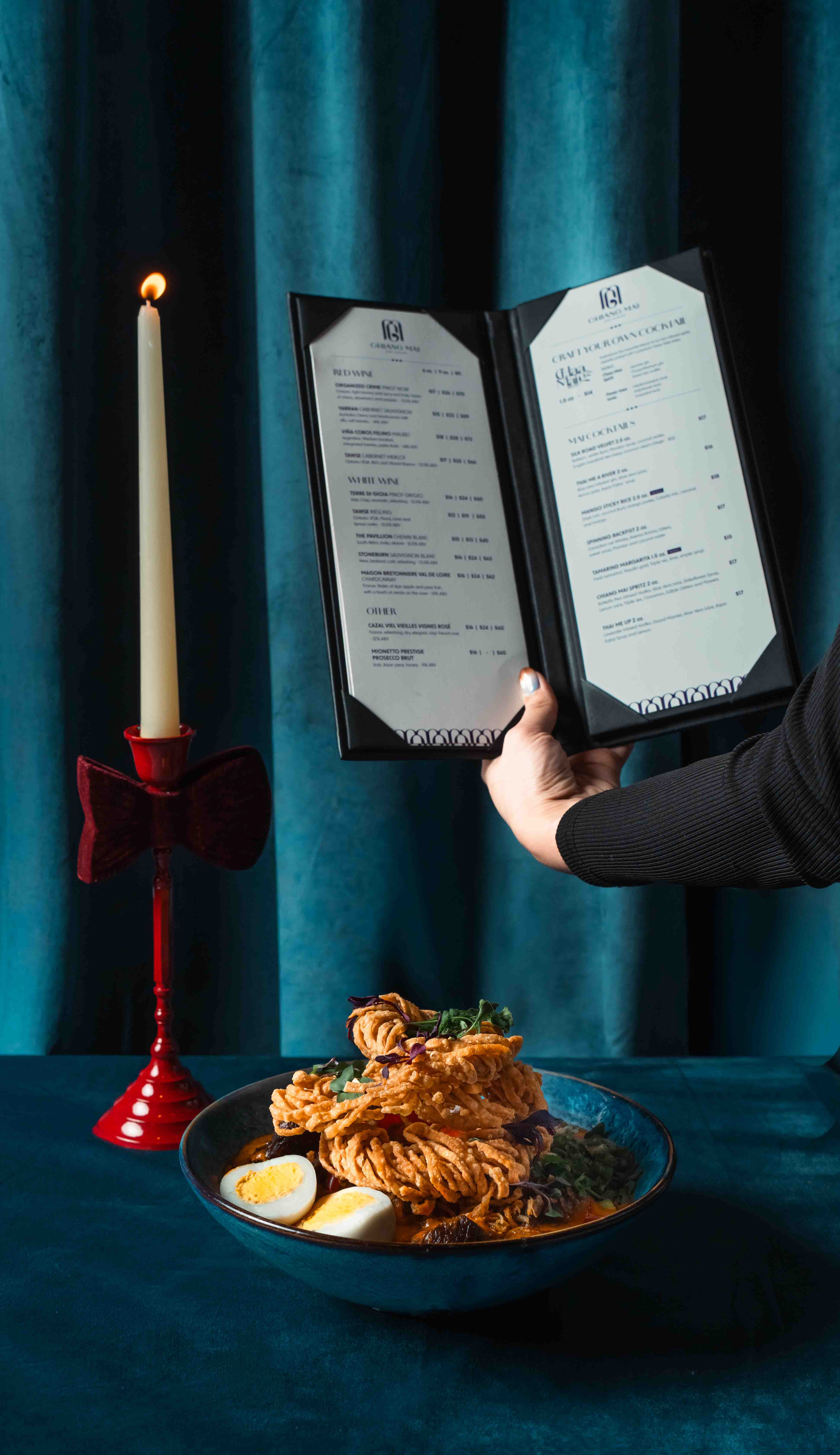 Professional editorial restaurant photography featuring a hand holding a menu next to a dish and candlelight, specialized hospitality branding services for dining establishments in Toronto and the GTA.