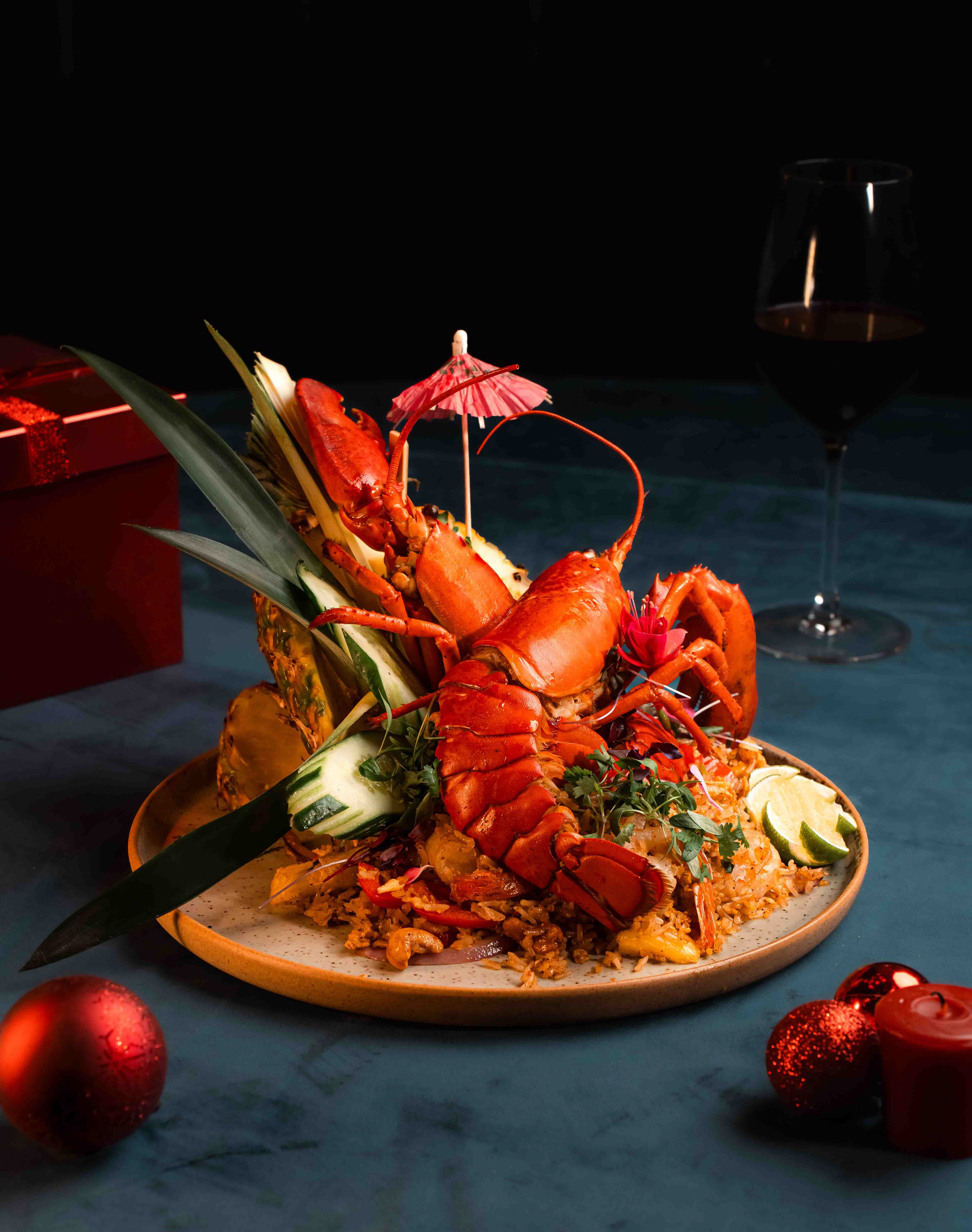 Luxurious holiday lobster and pineapple fried rice platter with festive red ornaments, food photography by Ash, a Toronto photographer specializing in seasonal restaurant menus and creative culinary styling.