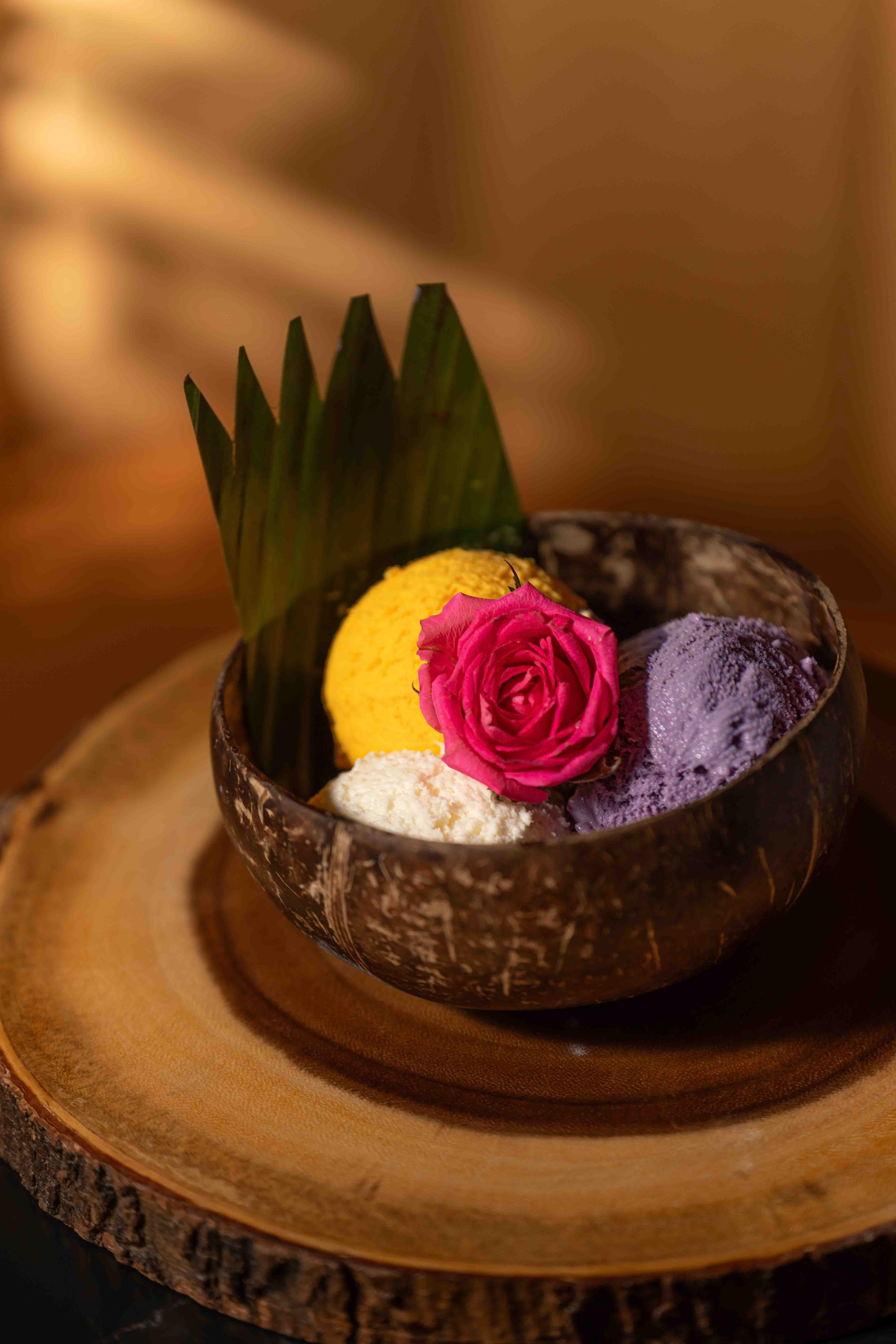 tropical ice cream scoops in a coconut bowl with a pink rose garnish, professional food photography for Toronto restaurants and dessert brands available across Canada.