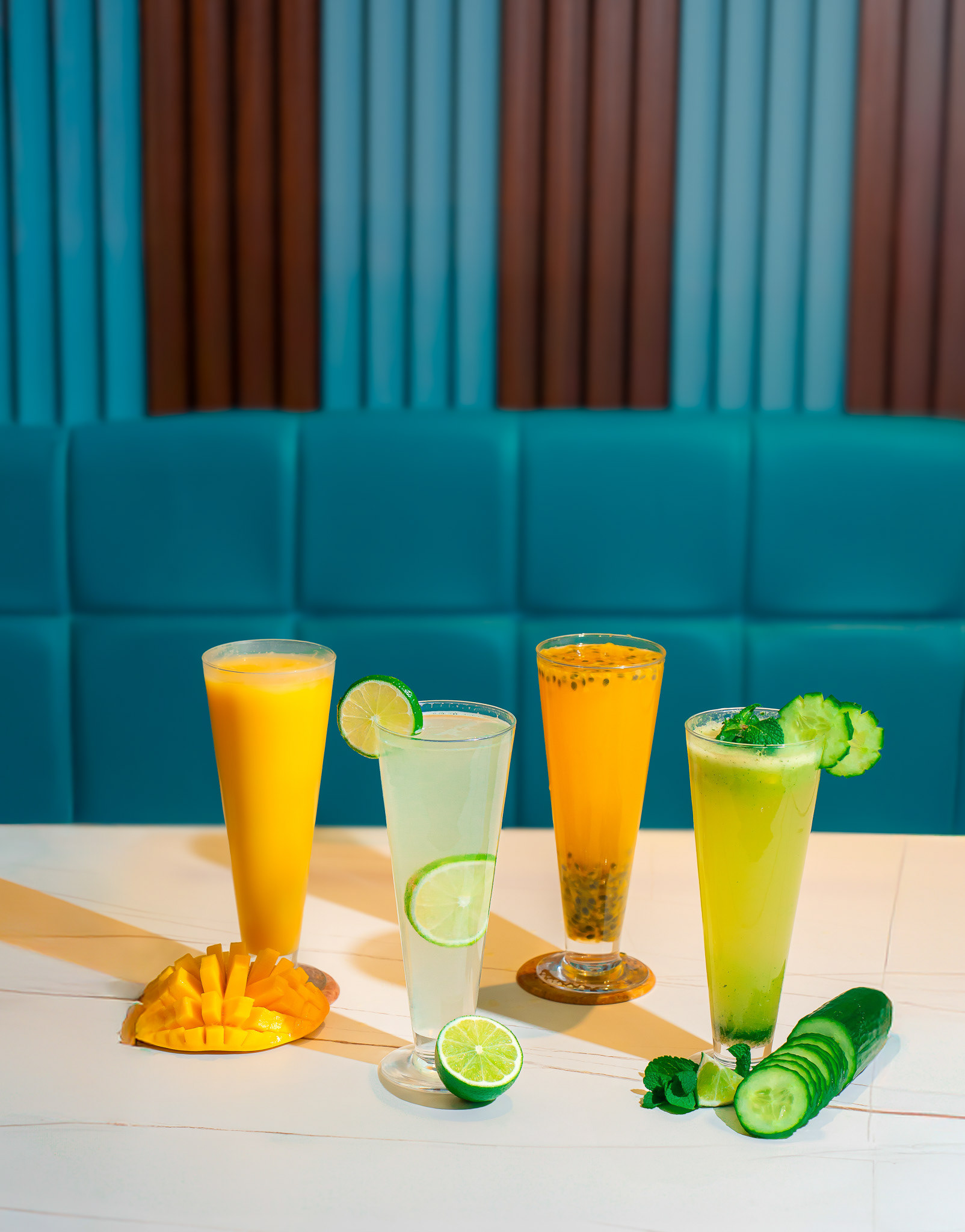 A professional food photographer in Toronto capturing the stunning image of a juice lined in bright light condition, the picture shows cinematographic aspects, it contains photographs of mango juice, mint lime, cucumber mint lime and passion fruit juice in a restaurant all lined for photography. It is suitable for menu design and food delivery platforms. A food photographer near me captured this beautiful image