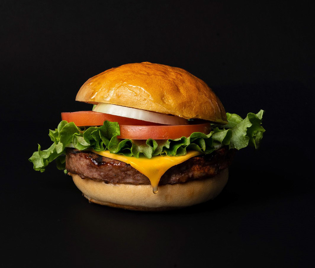 Professional commercial food photography of a  cheeseburger with fresh lettuce and tomato by Ash, a Toronto food photographer serving restaurants and brands across Ontario.