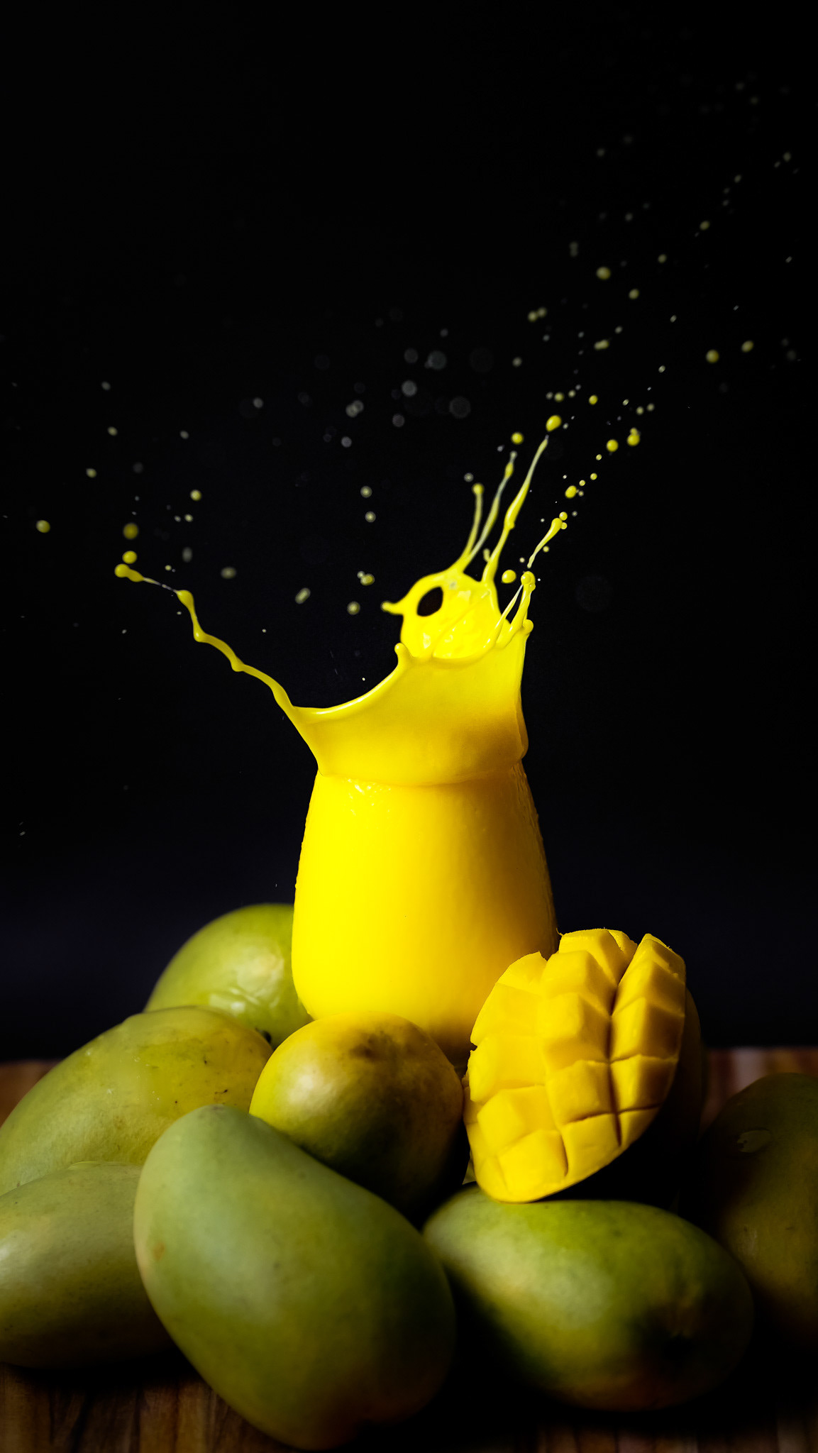 High-speed commercial splash photography of a vibrant mango lassi surrounded by fresh mangoes, specialized beverage motion photography for Toronto-based Indian restaurants and juice brands.
