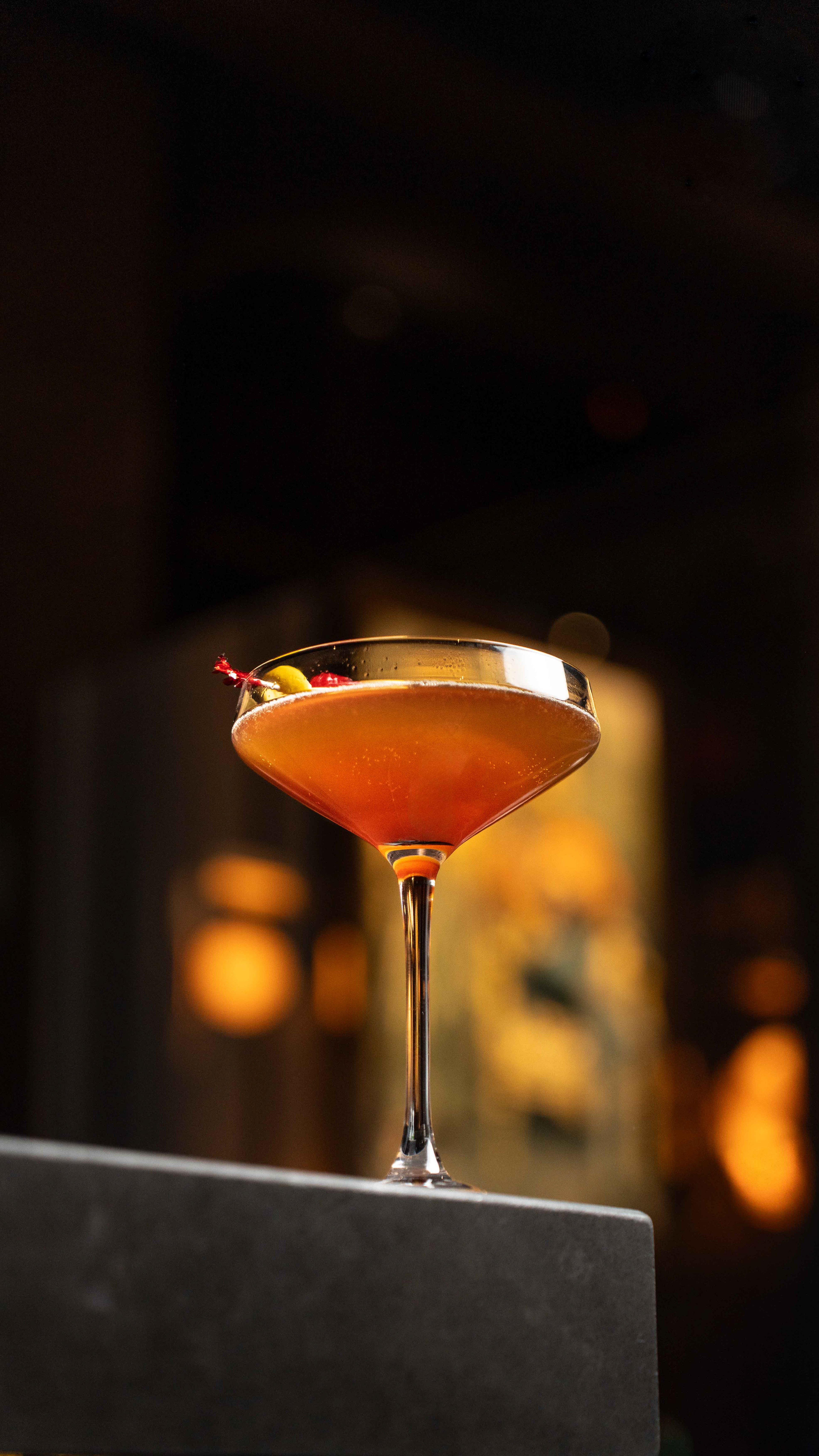 Sophisticated martini cocktail with olive garnish in a dimly lit bar setting, professional beverage photography by Ash, serving hospitality and nightlife clients in Toronto and throughout Canada.