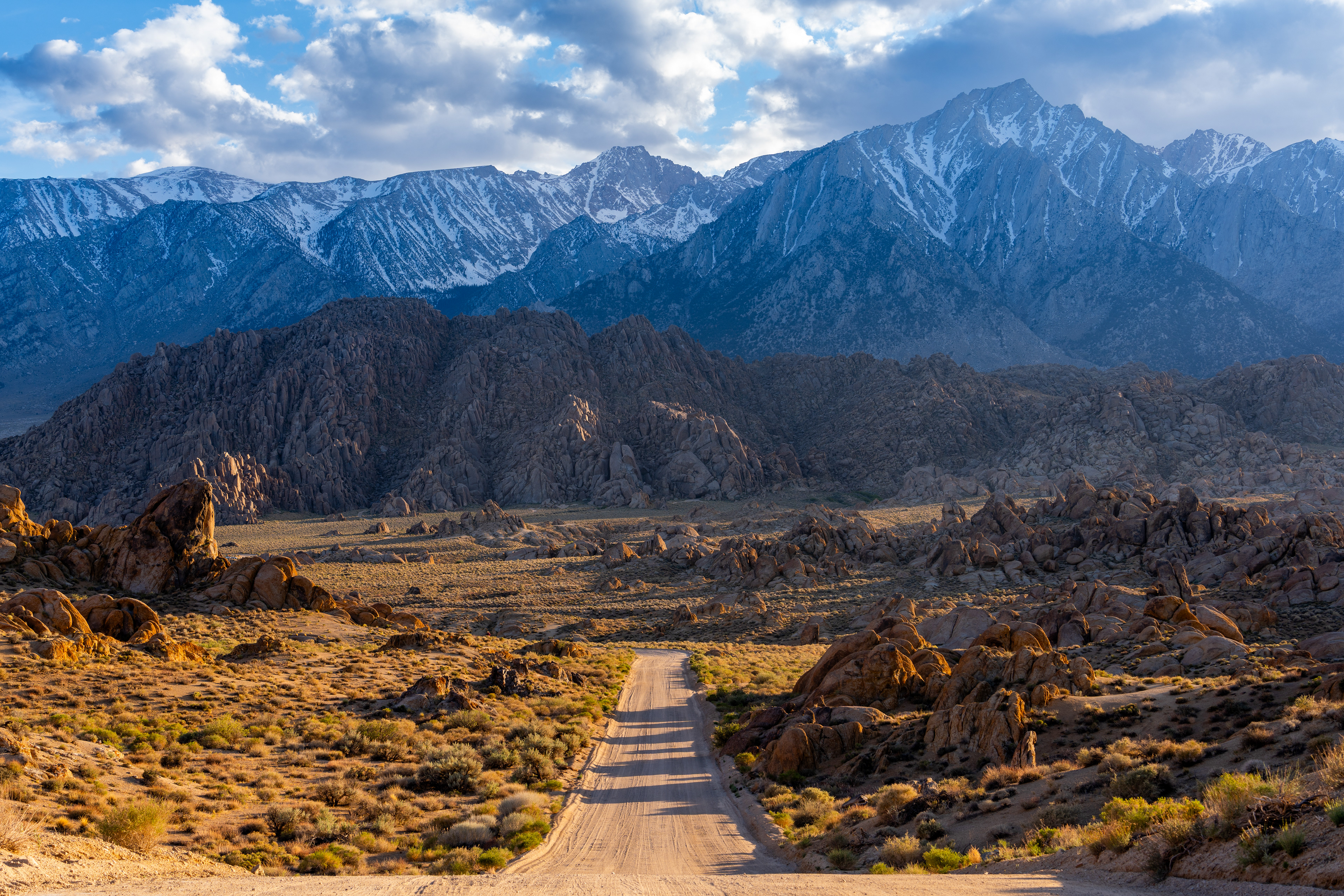 Dirt road leading into the rocky landscape of Alabama Hills with the Sierra Nevada mountains in the background at golden hour, 2025. Landscape photography by Shaw Horton.