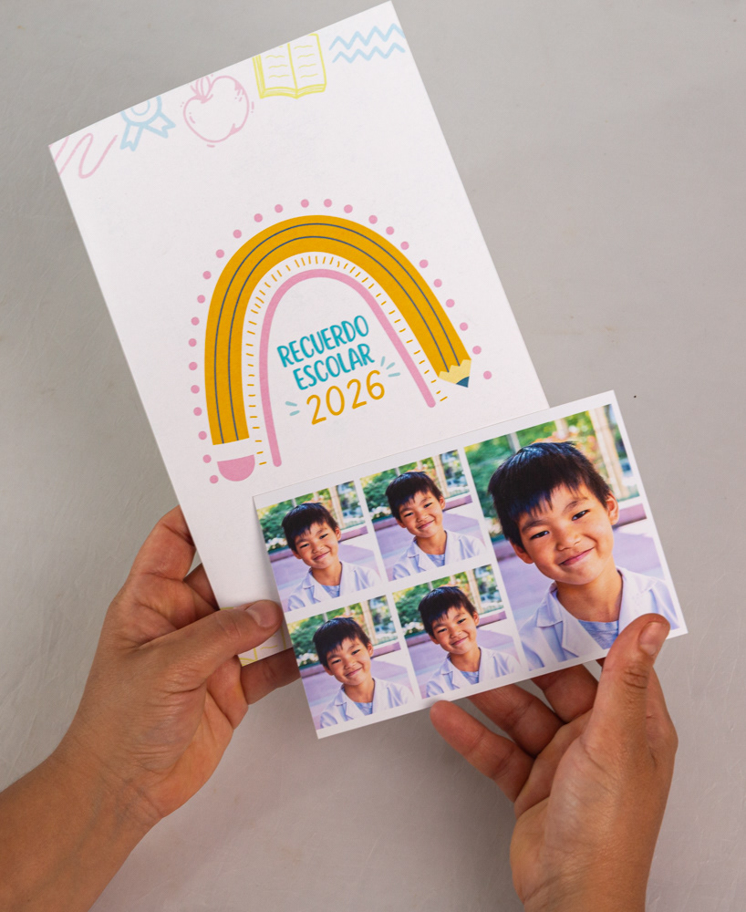 Manos sosteniendo formato 10x15 cm con cuatro fotos carnet de 4x4 cm y una foto de recuerdo de 6x9 cm. Niño con guardapolvo blanco sonriendo, fondo de escuela desenfocado con luz natural. Producto adicional 2026 de Retratos Escolares, fotografía escolar en CABA y Gran Buenos Aires.