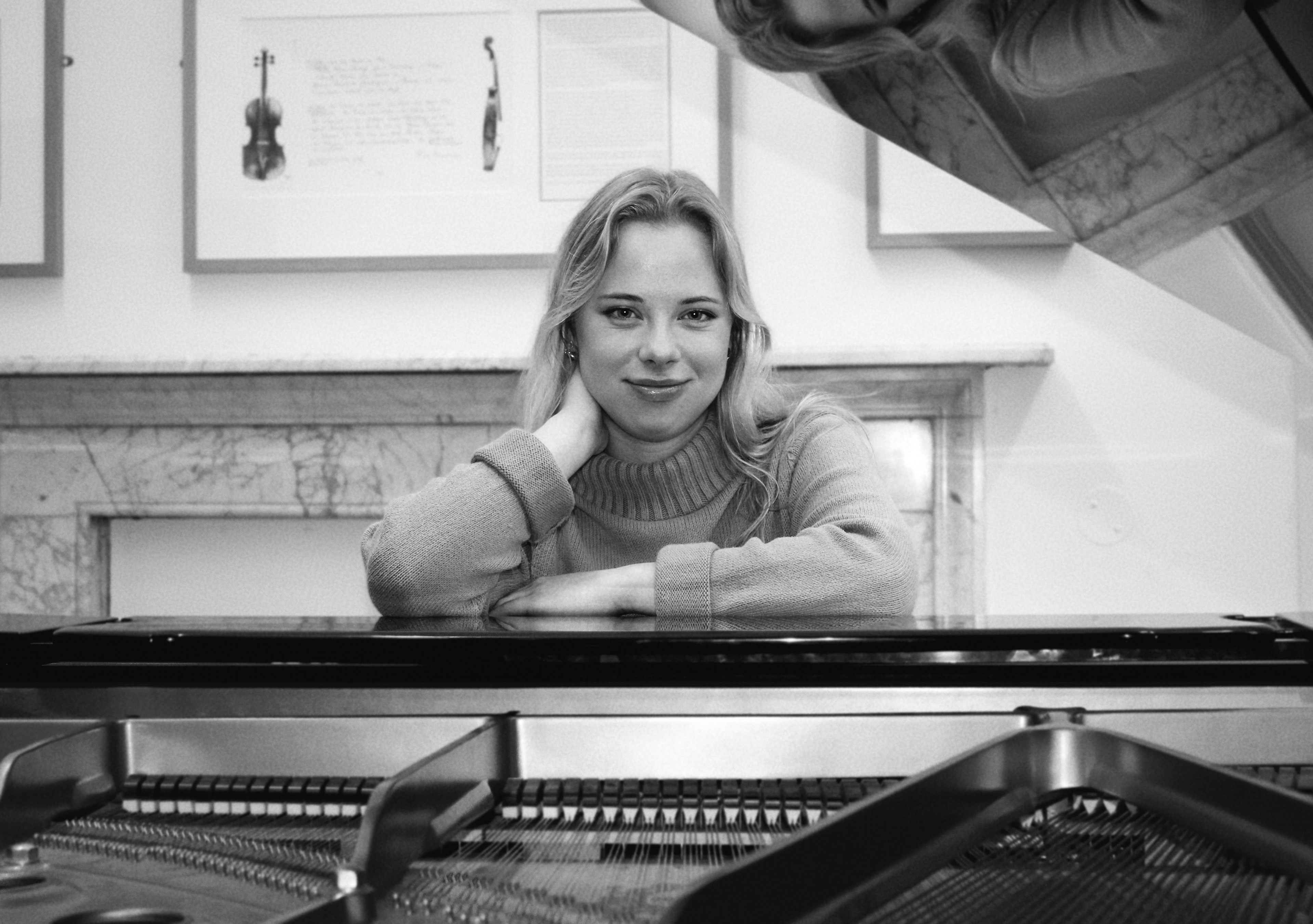 Polina Savicka, composer and piano teacher, sitting at a grand piano