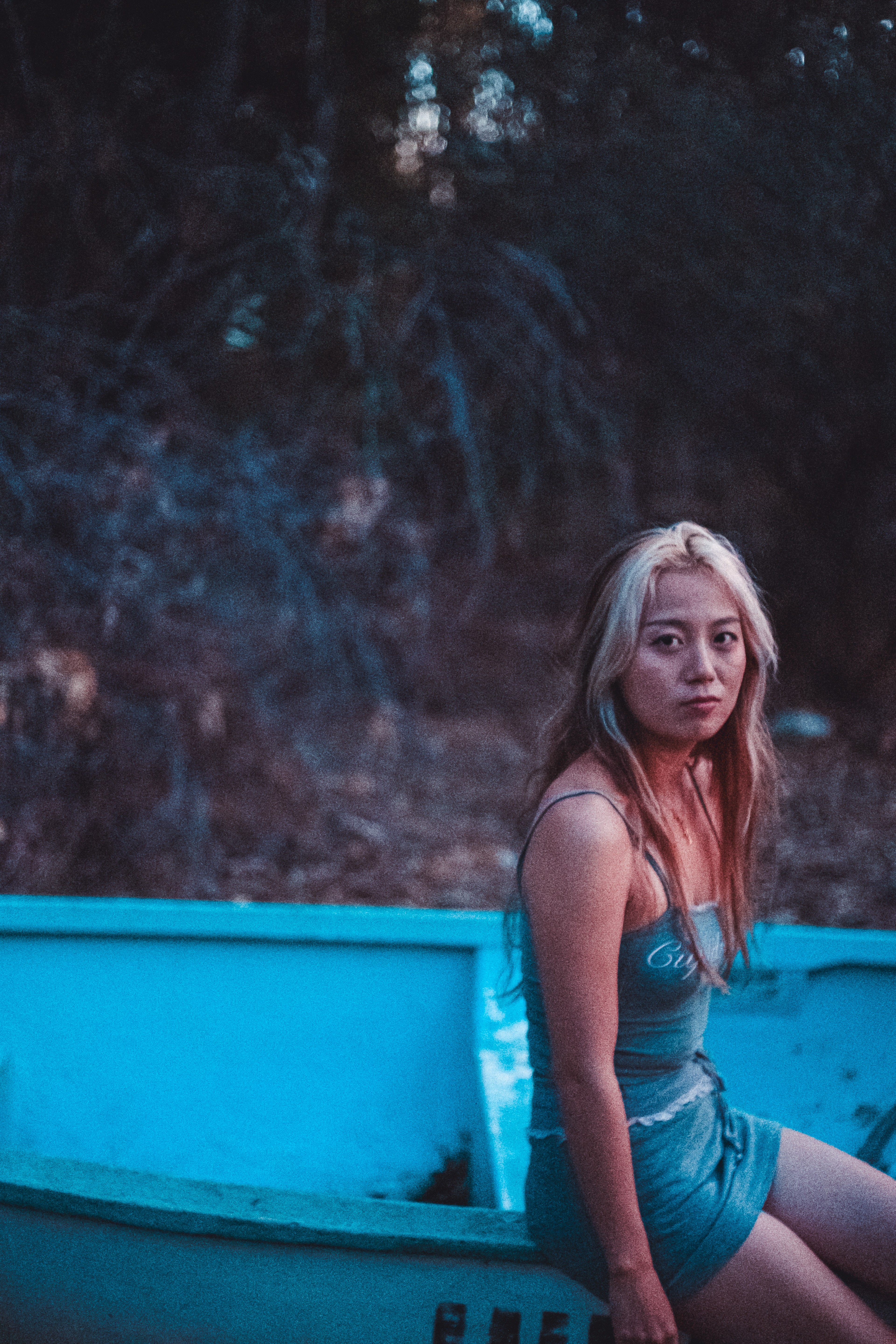 Young woman with blonde hair sitting in a boat at golden hour in Yanchep National Park, soft cinematic mood