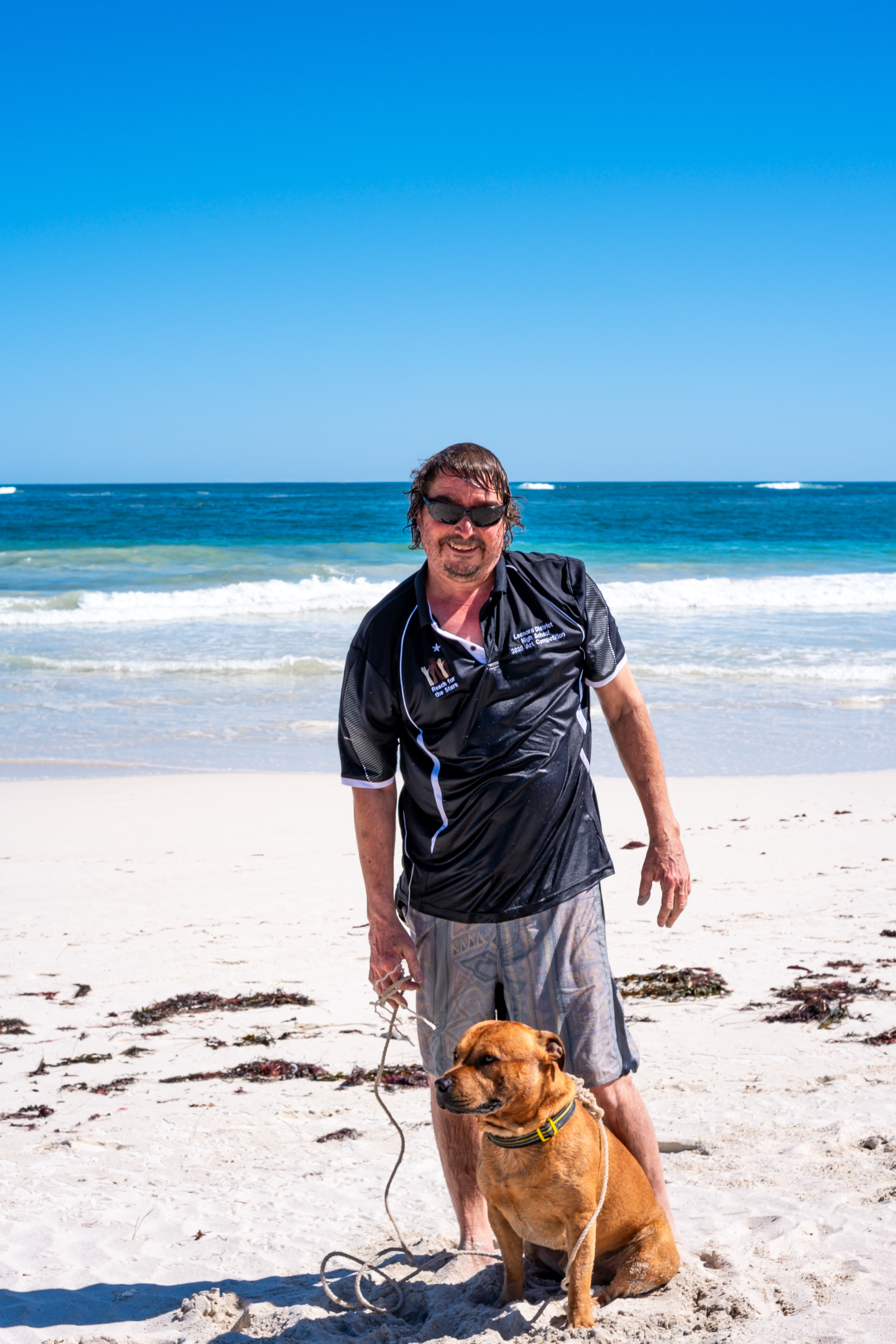 Natural candid moment between a man and his dog on the sand of Lancelin