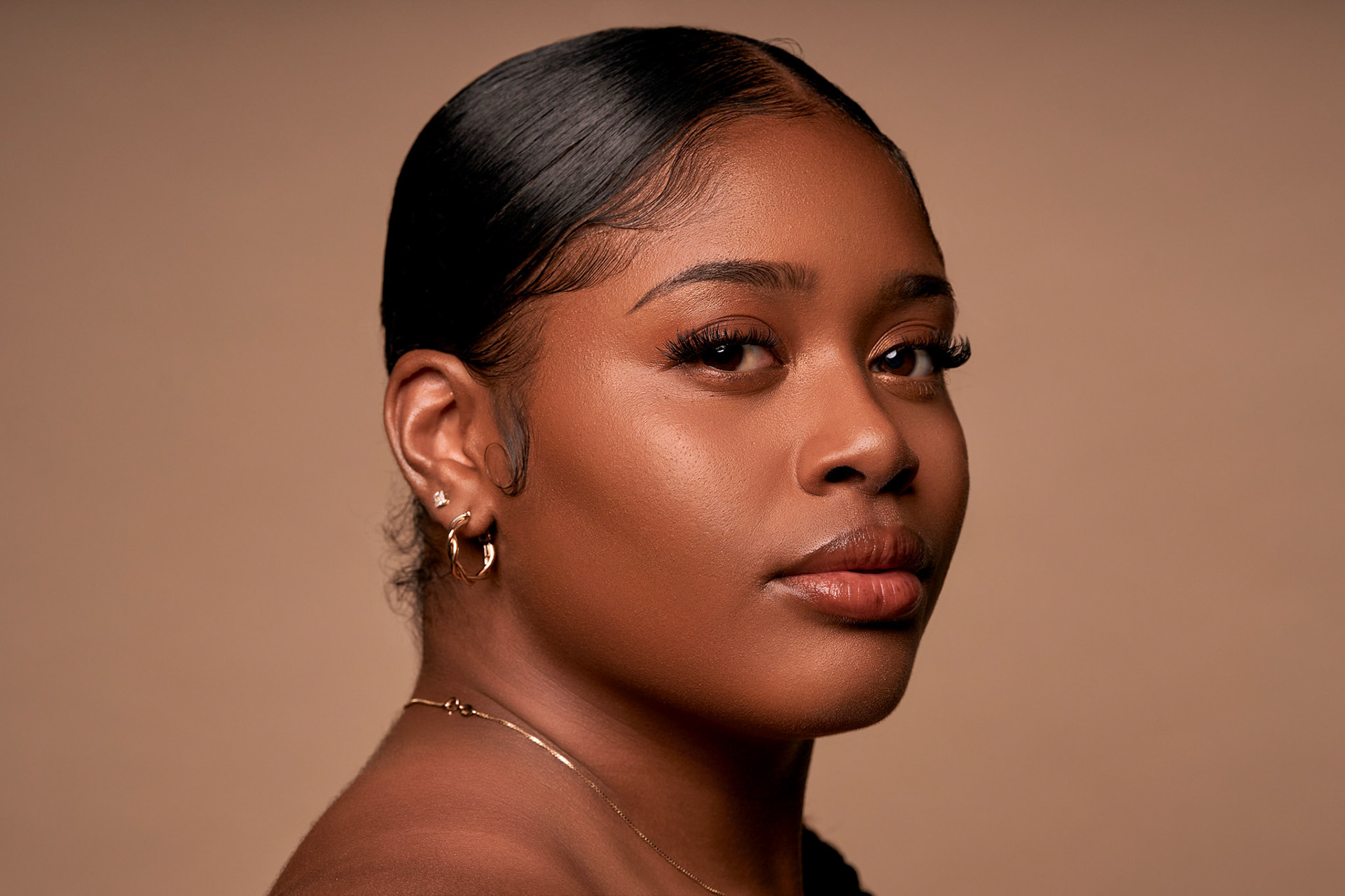 Beauty close-up with sleek hair against a warm tan background