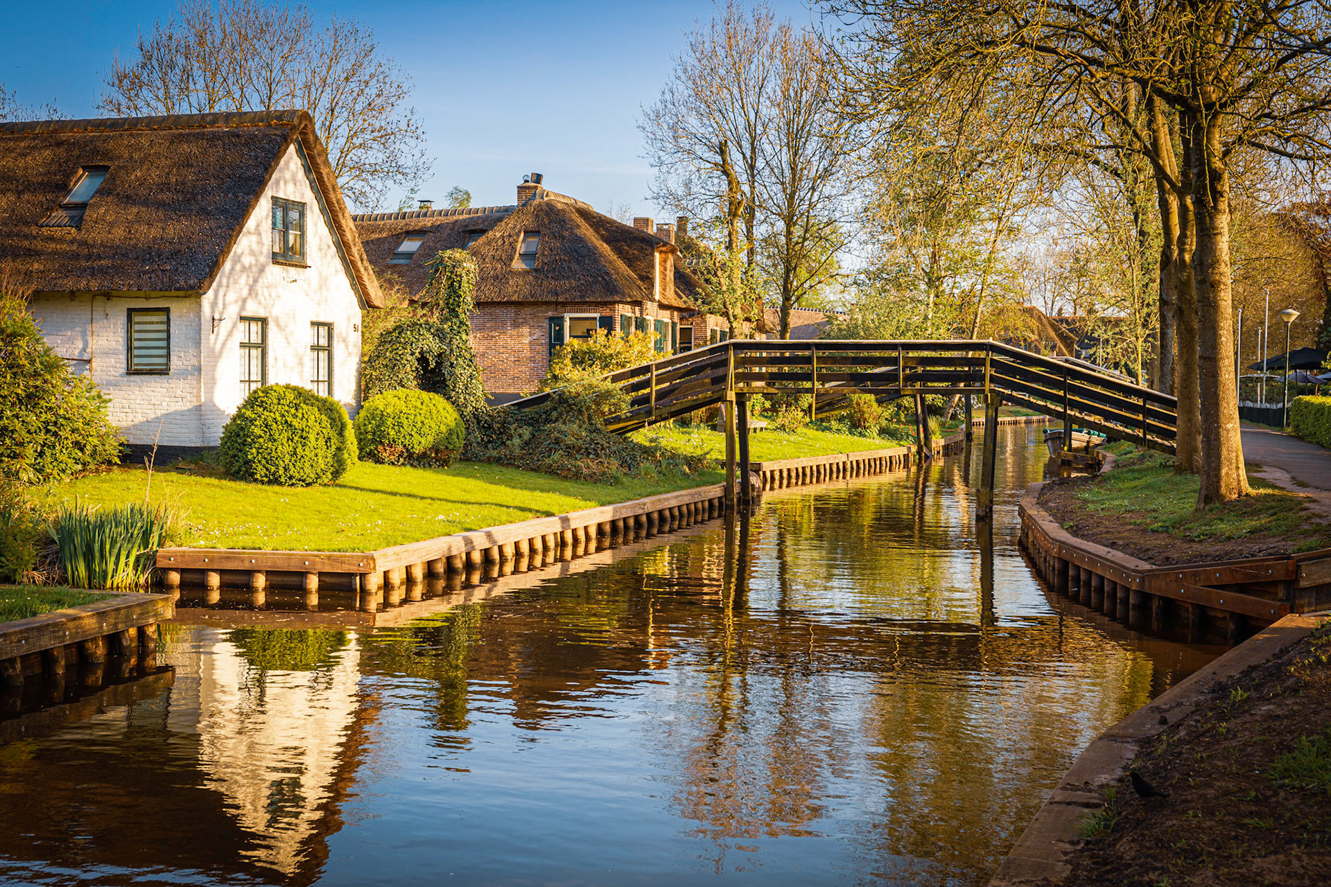 Lovely landscape along canal with footbridges and beautiful thatched cottages, Giethoorn, Netherlands
