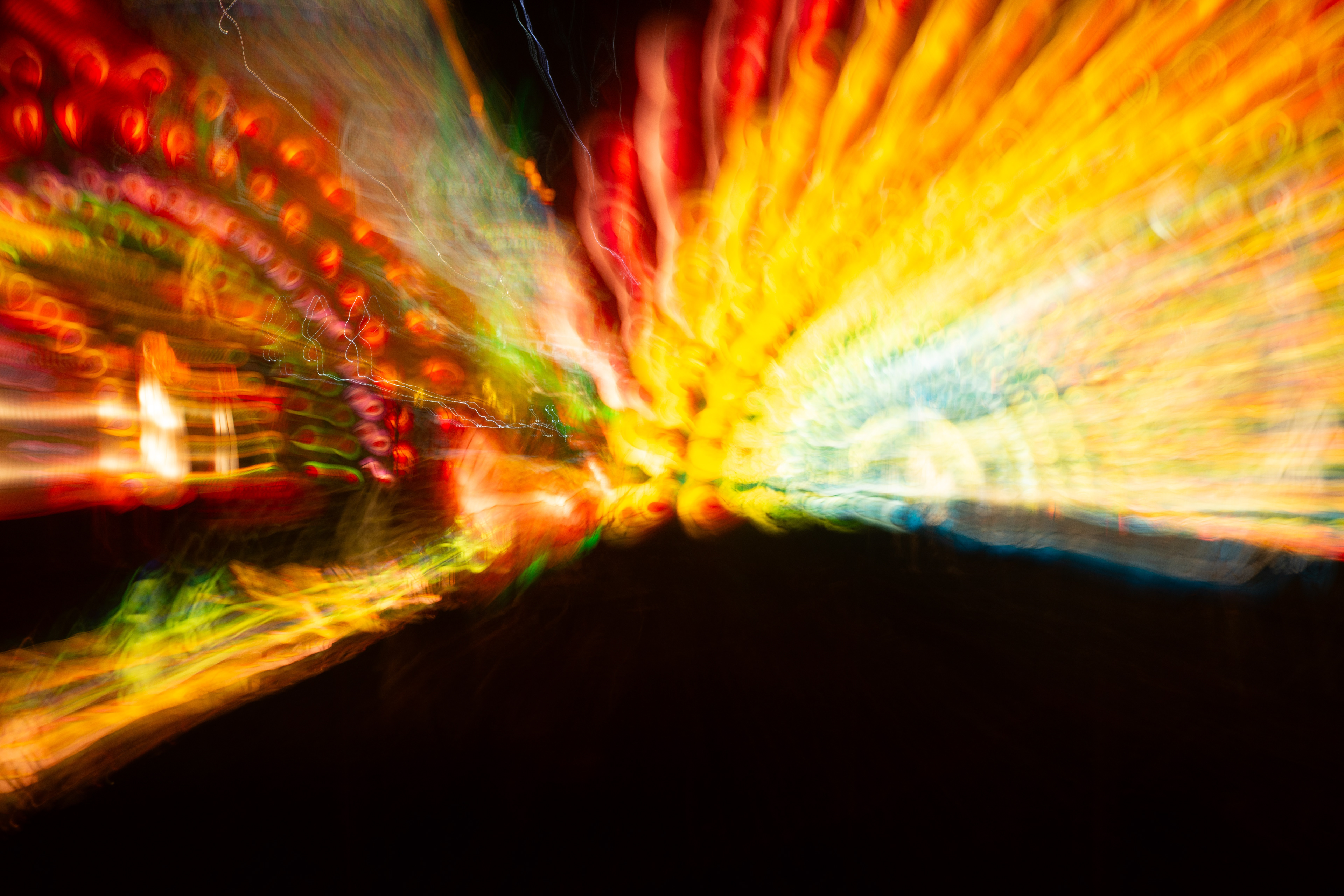 'Rainbow' (2018). A mesmerising explosion of colours dances across the canvas, as if a kaleidoscope of neon hues has been set free in the night. Fiery reds and oranges blaze like a sunset igniting the horizon, while electric blues and greens weave through the scene like ethereal ribbons. The lights stretch and swirl, creating a sense of motion and energy, reminiscent of a cosmic event or a carnival in full swing. The dark backdrop serves as a perfect stage, allowing the vibrant spectacle to shine with an almost otherworldly brilliance.