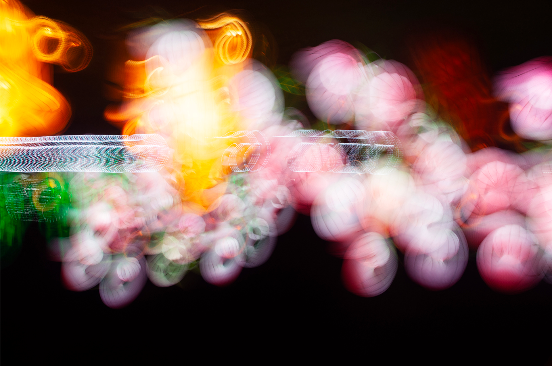 'Colourful Bubbles' (2018). A hypnotic, surreal painting of colours against a dark canvas, where soft orbs of pink and white float like bubbles. Hints of green weave through the scene, reminiscent of a hidden garden. Fiery bursts of orange and yellow flicker like distant lanterns, casting a warm glow. The entire composition feels like a dreamscape, where light and colour blur the boundaries of reality.