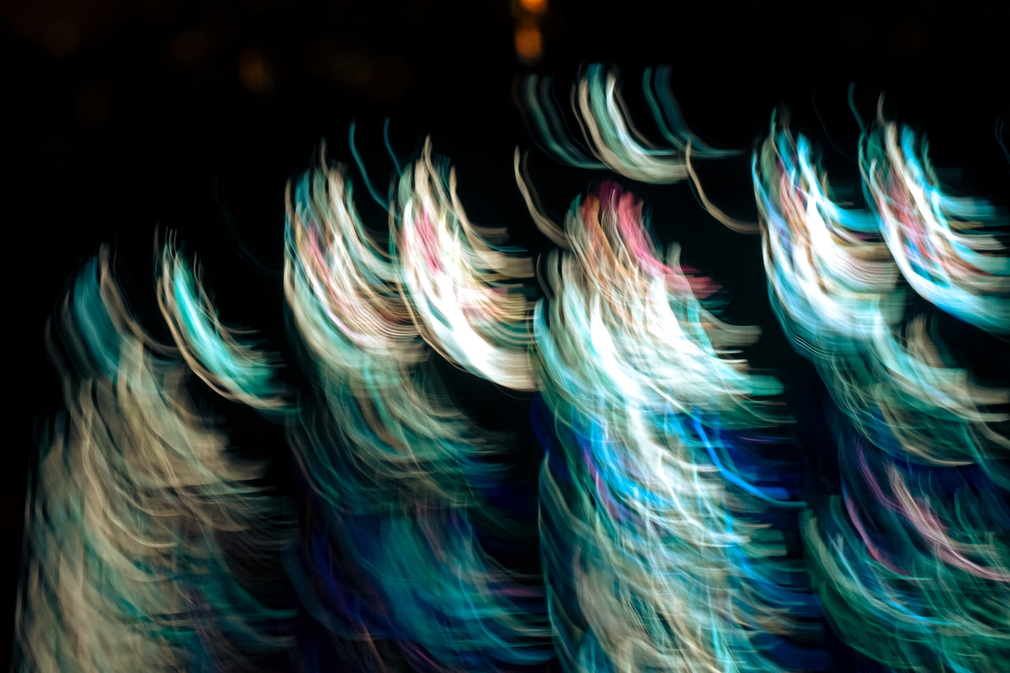 'Illuminated Seaweed' (2025) Waves of luminous colour sweep across a deep black canvas. Electric turquoise, icy white, and vivid aquamarine dominate the arcs, with bursts of magenta and hints of gold flickering through the movement. The texture is silky and feathery, as if painted with quick brushstrokes or layers of translucent fabric, each glowing strand blurring into the next. The colours undulate with a shimmering, ethereal quality, giving the impression of both motion and softness—like reflections twisting on water at night or the trailing lights of dancers swirling in vibrant costumes. Each streak blends into the surrounding darkness, creating a tapestry of illuminated threads and rippling colour.