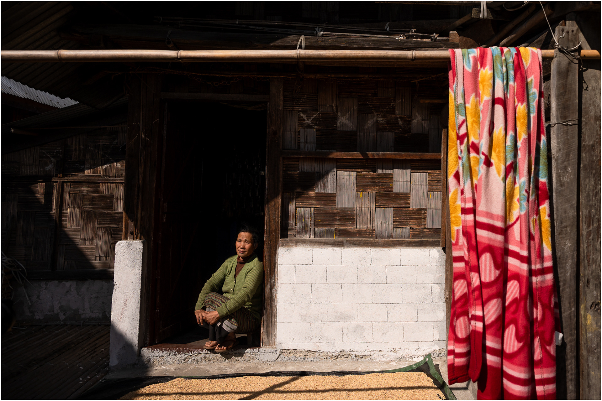 An Apatani woman sits in front of harvested rice