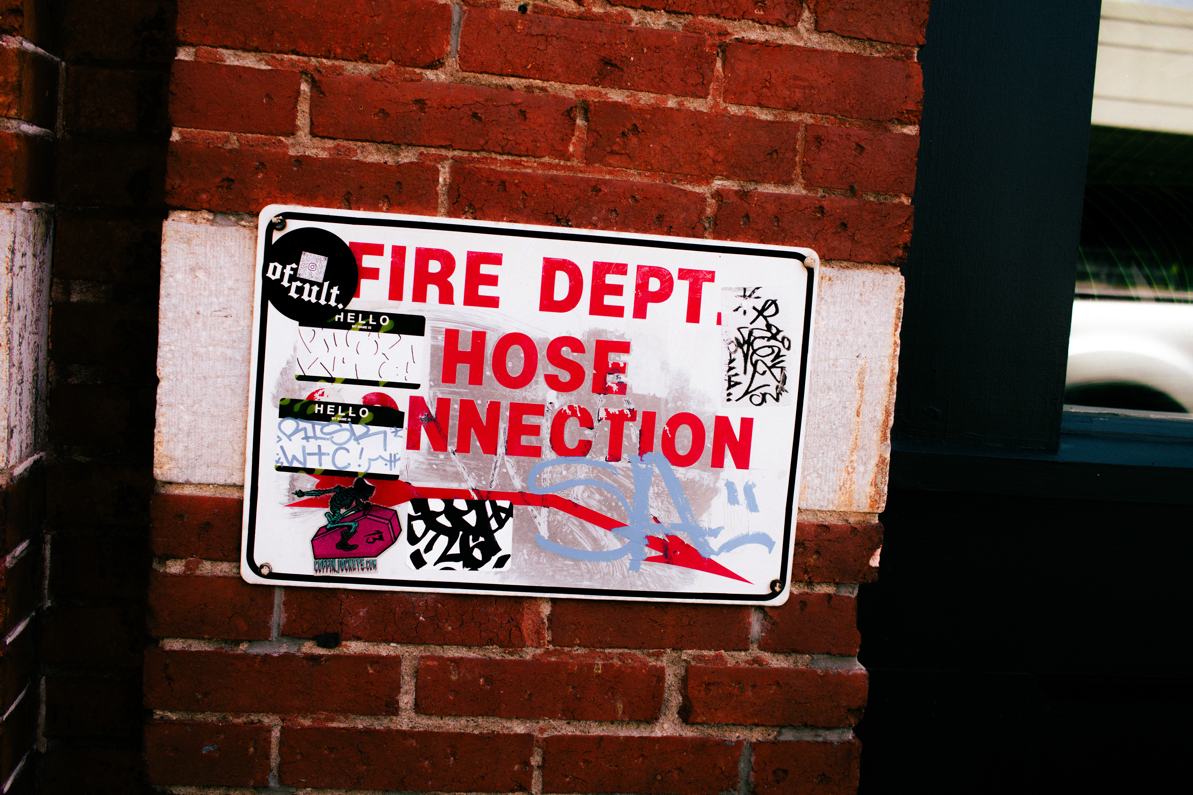 Fire department sign covered with overlapping stickers, graffiti, and markings.