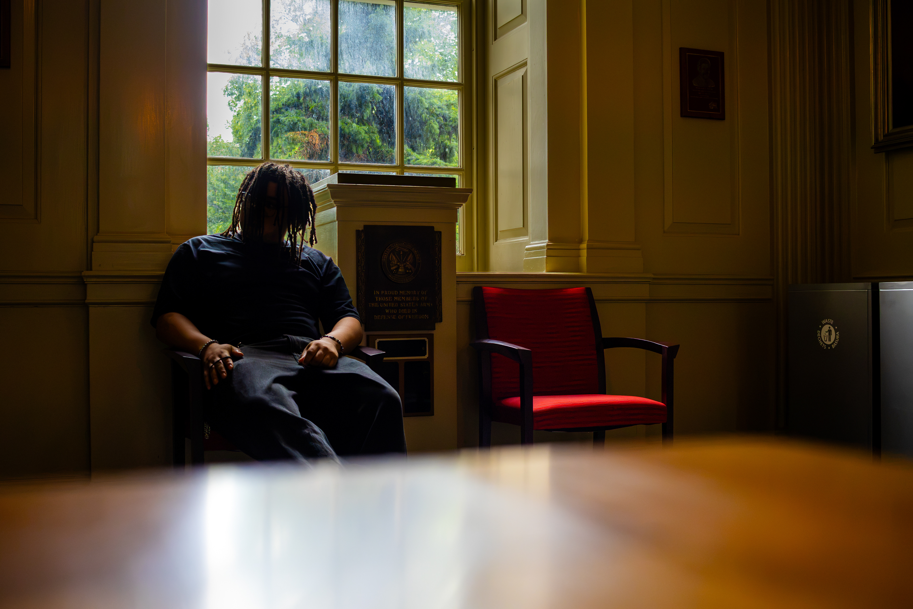 Person sitting in a quiet room, framed by a large window and warm afternoon light.