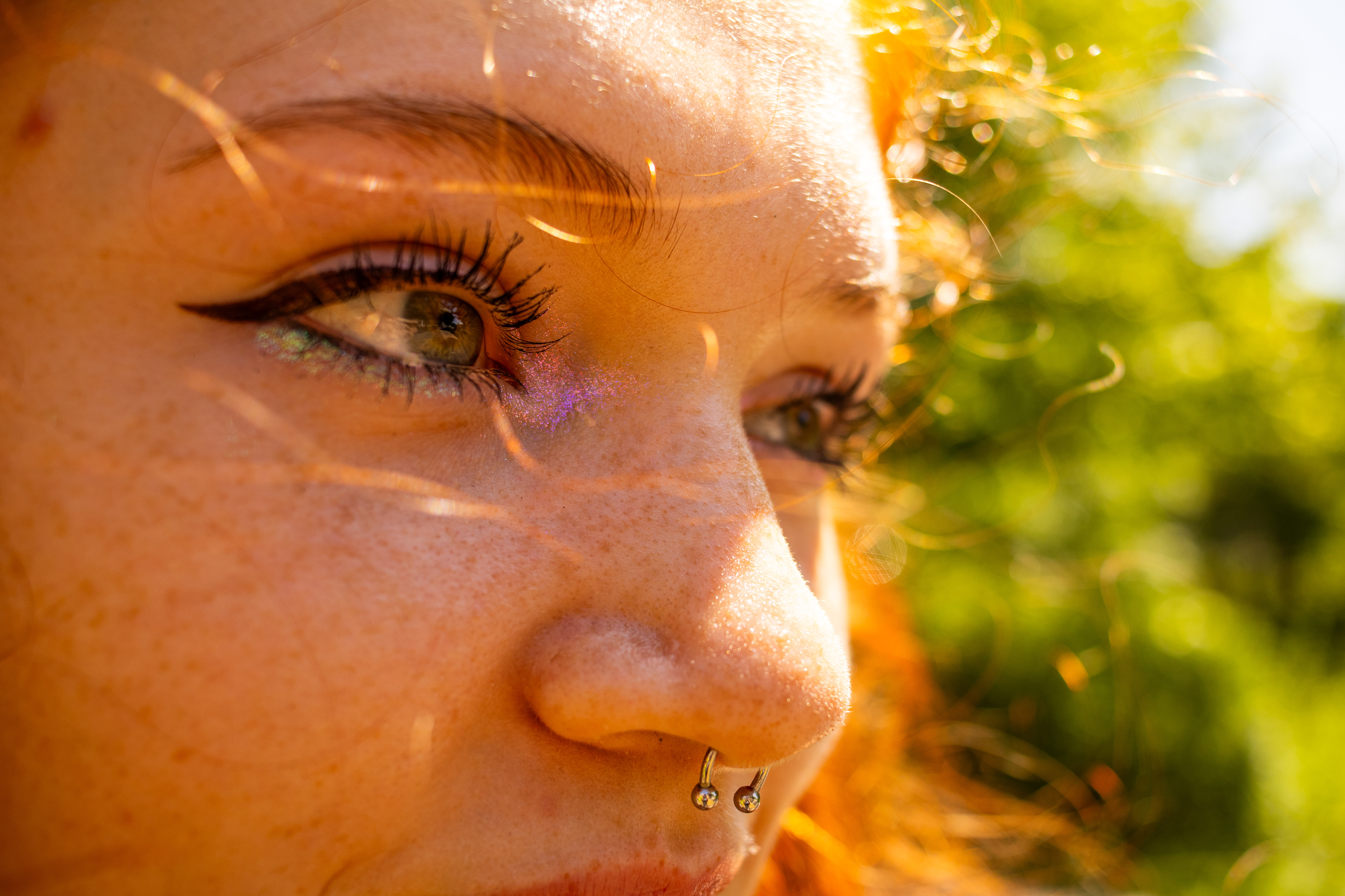 Close-up portrait highlighting a person's eye, freckles, and facial details.