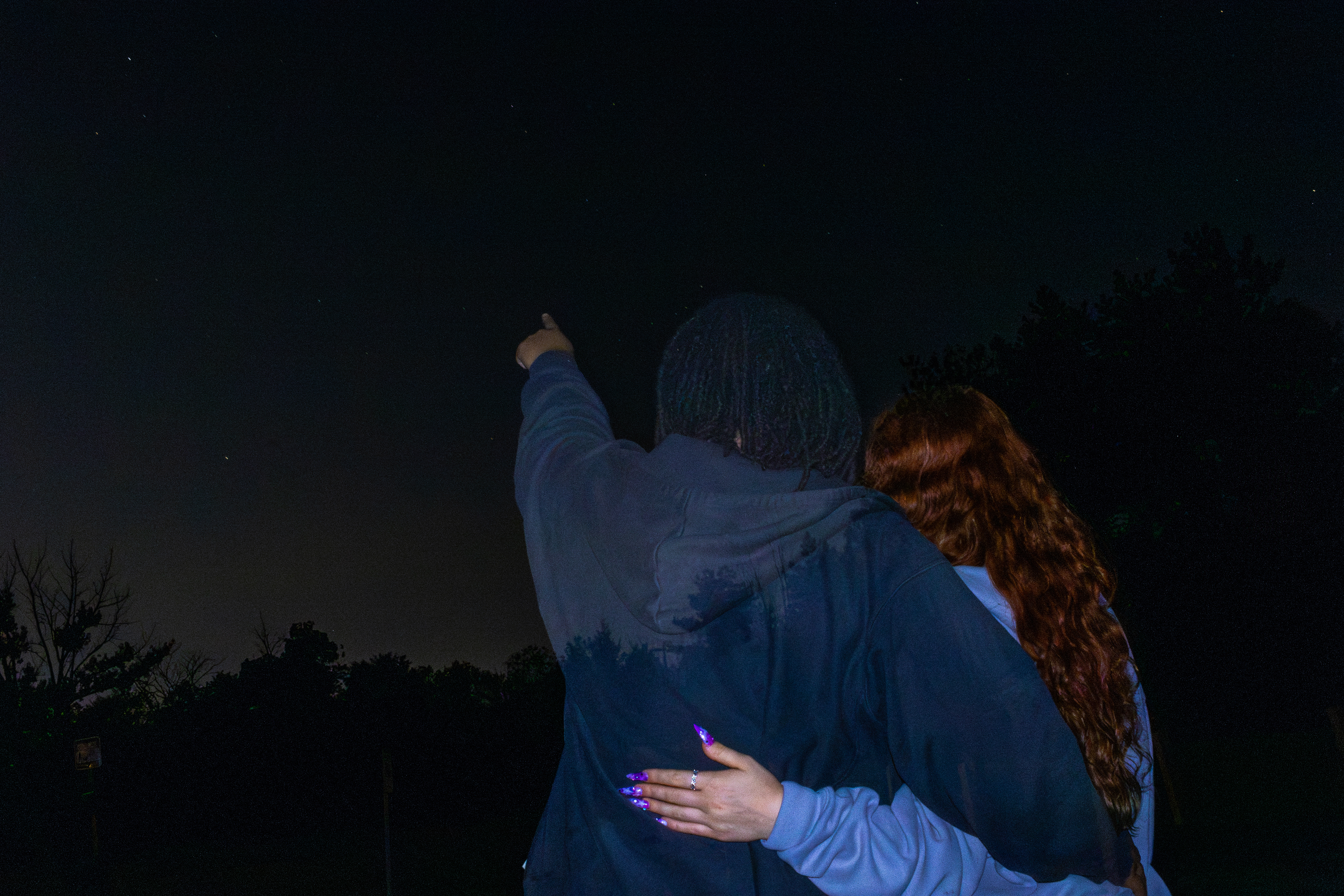 Couple embracing beneath the night sky.