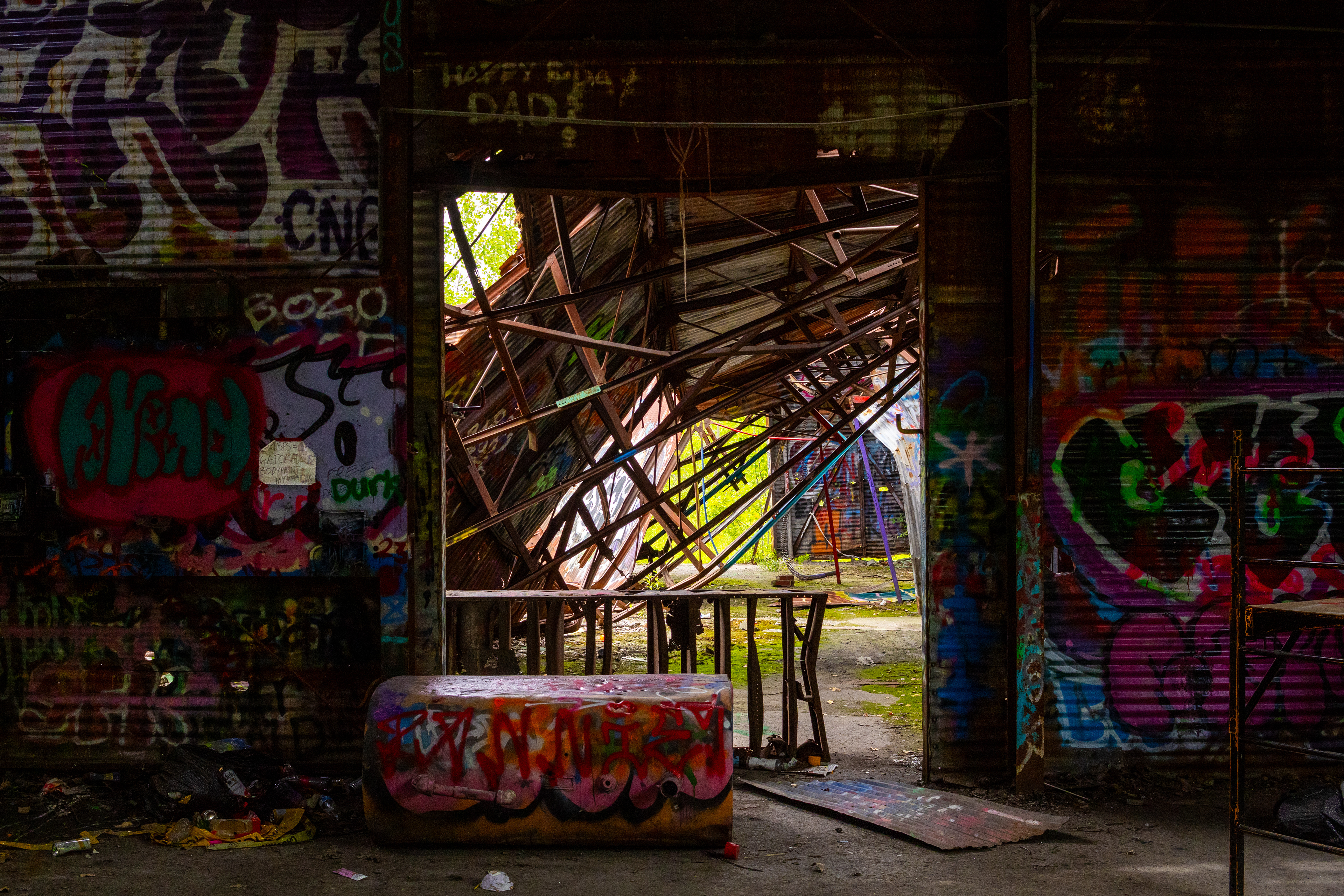 Abandoned interior covered in colorful graffiti, with sunlight filtering through the damaged structure.