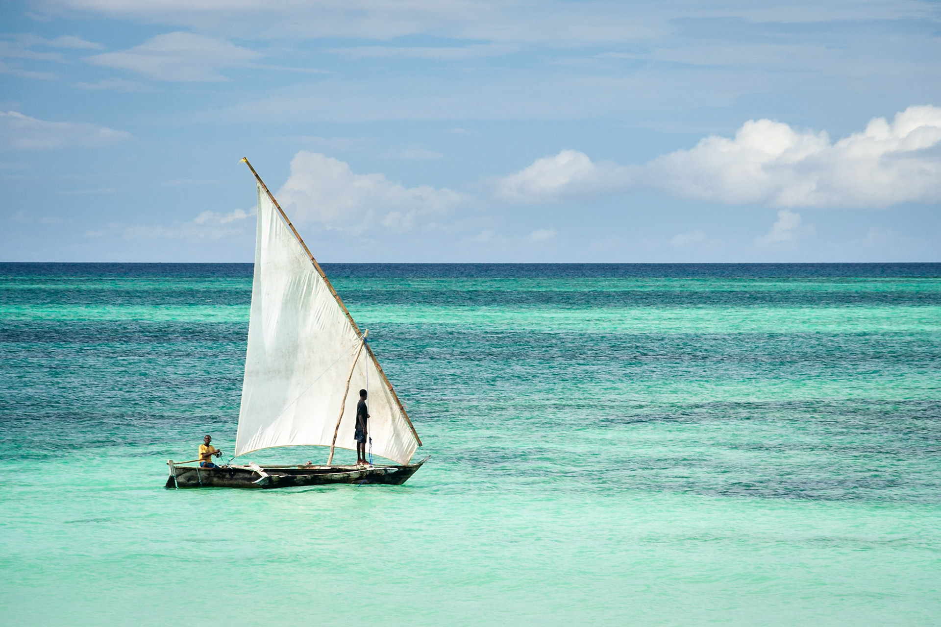 Two boys sail a dhow off the coast of Zanzibar.