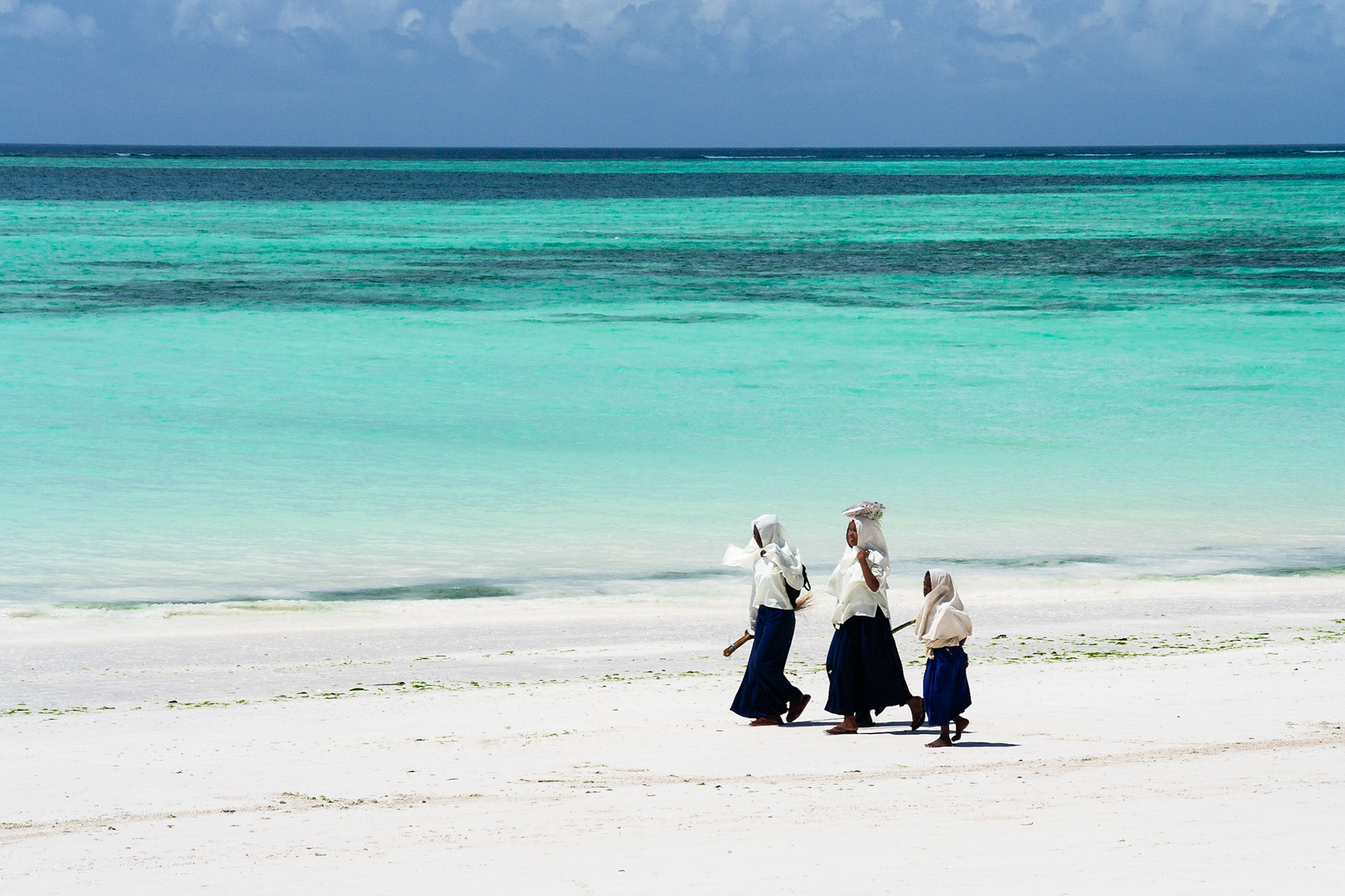 Girls head home from school using the beach as their path, Zanzibar.