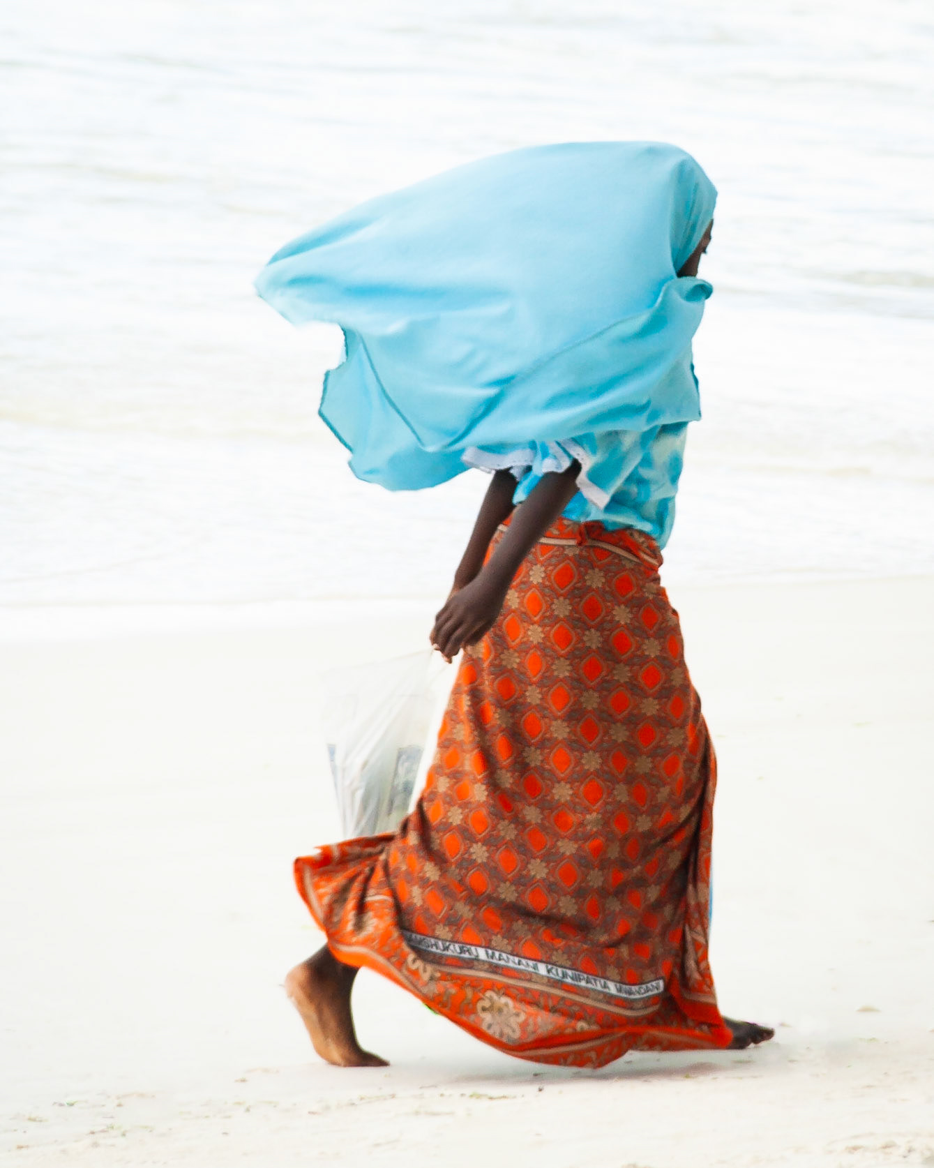A young girl walks with purpose along the beach, Zanzibar.