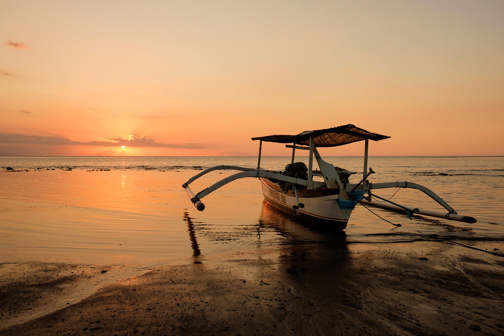 A sunset, a boat and a fisherman, Lovina beach, Bali, Indonesia.