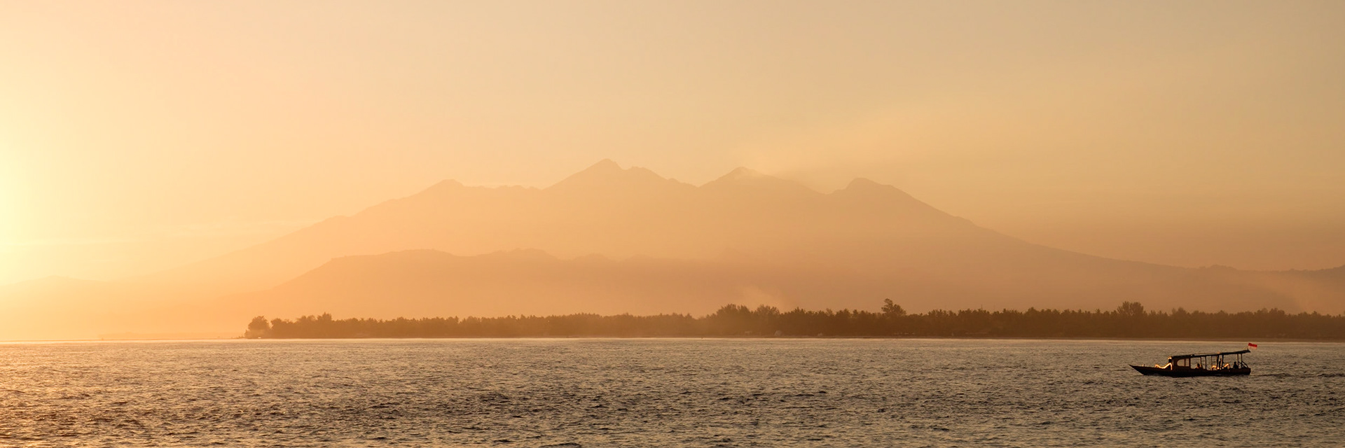 A boat passes Gili Air and Lombok at sunrise, Gili Meno, Lombok, Indonesia.
