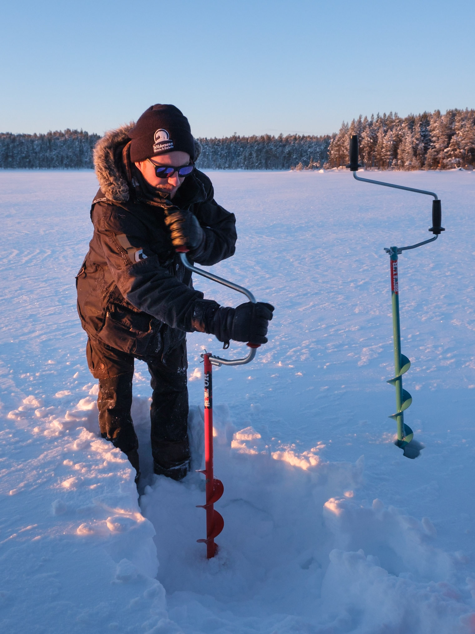 Time to try some ice fishing. Jonny demonstrating how to drill a hole, Nellim, Finnish Lapland.