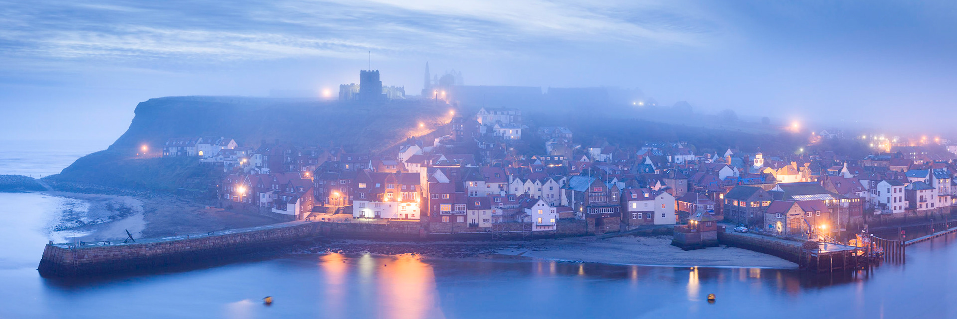 Misty dawn over Whitby's east side with the Whitby Abbey on the hill, Whitby, England.