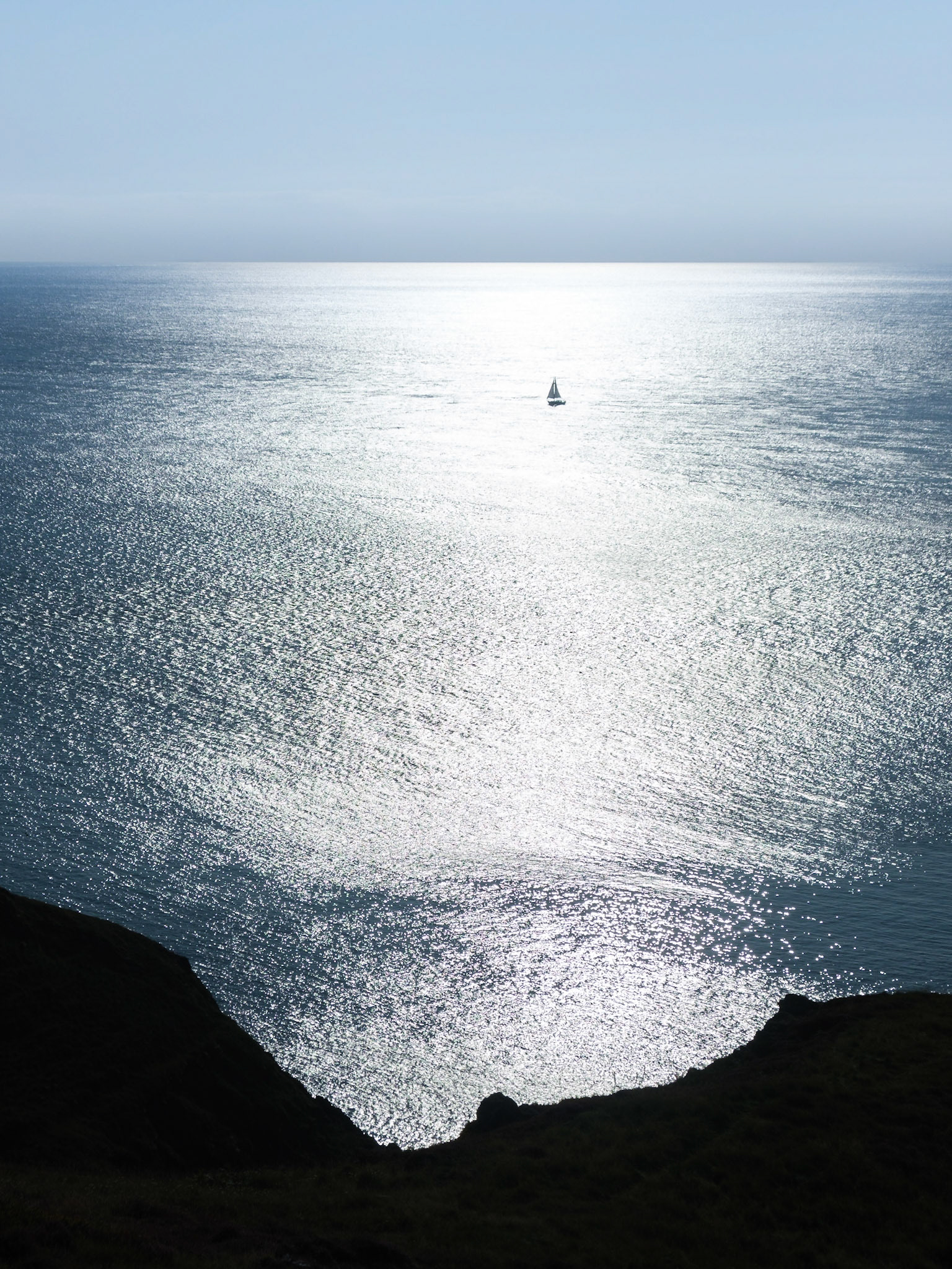 Sailboat rounding Carmel Head on passage to Holyhead.