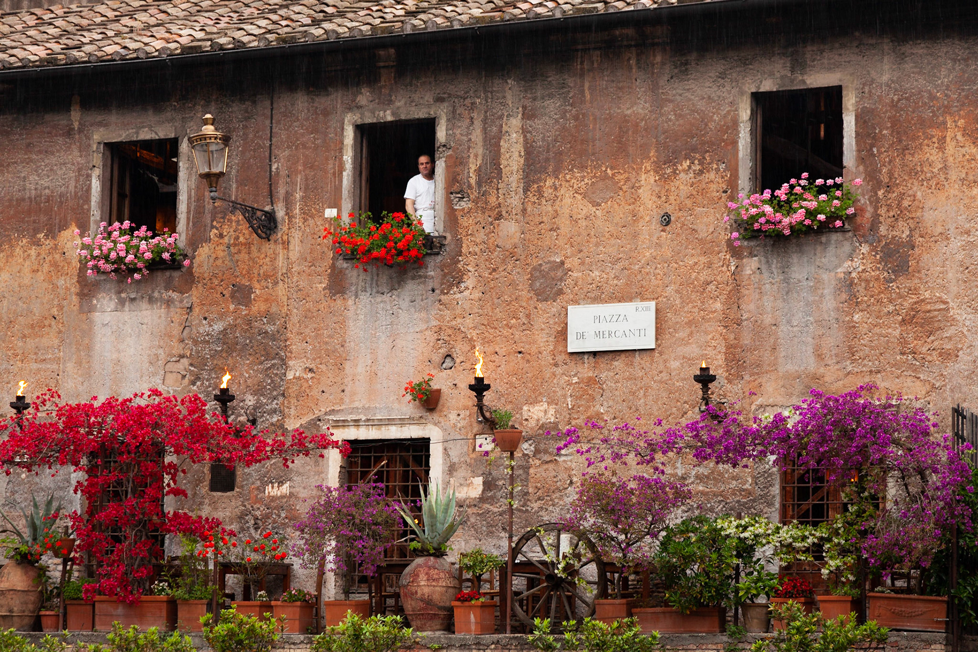 A chef looks out across Piazzi de Mercanti from a window of his restaurant, Rome, Italy.