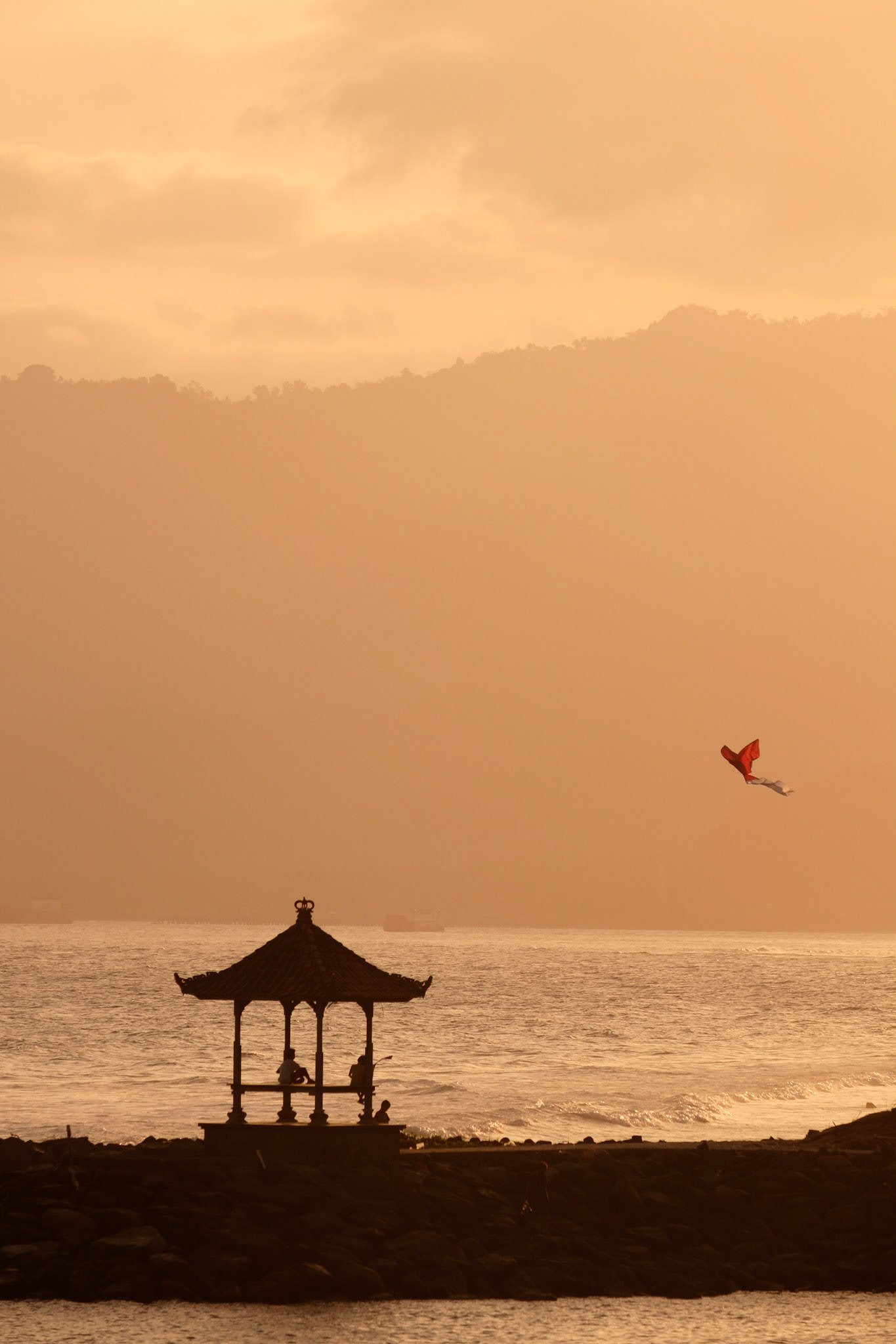 Some Balinese kids flying their kite at sunset on Candidasa beach, Bali, Indonesia.