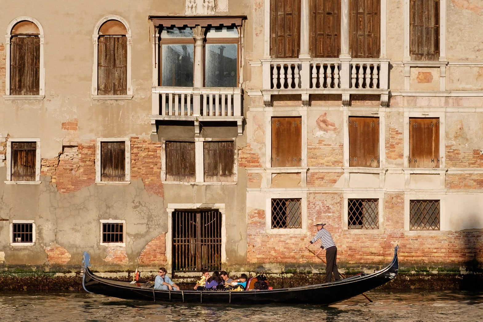 Tourists enjoy a gondola ride along the Grand Canal in the late afternoon, Santa Croce, Venice.