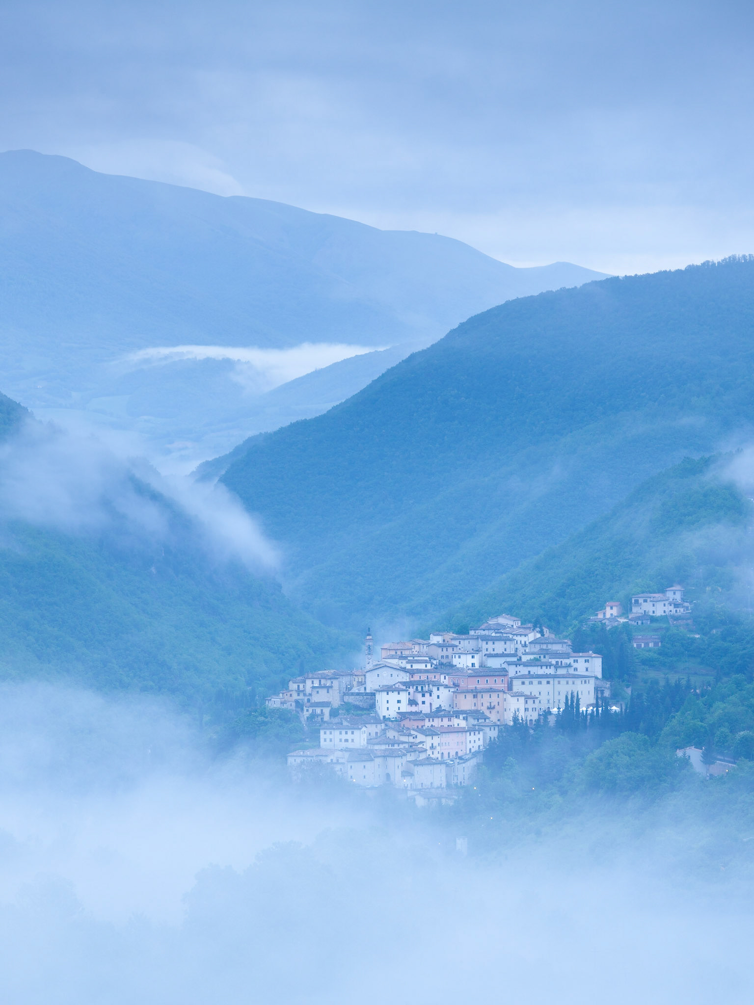 The town of Preci is revealed as the mists disperse on a spring morning, Umbria, Italy.