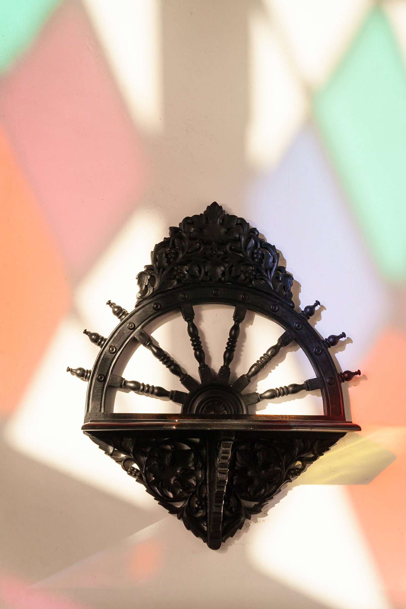 A wooden carving on a wall lit through a stained glass window, Tembo Hotel, Stonetown, Zanzibar.