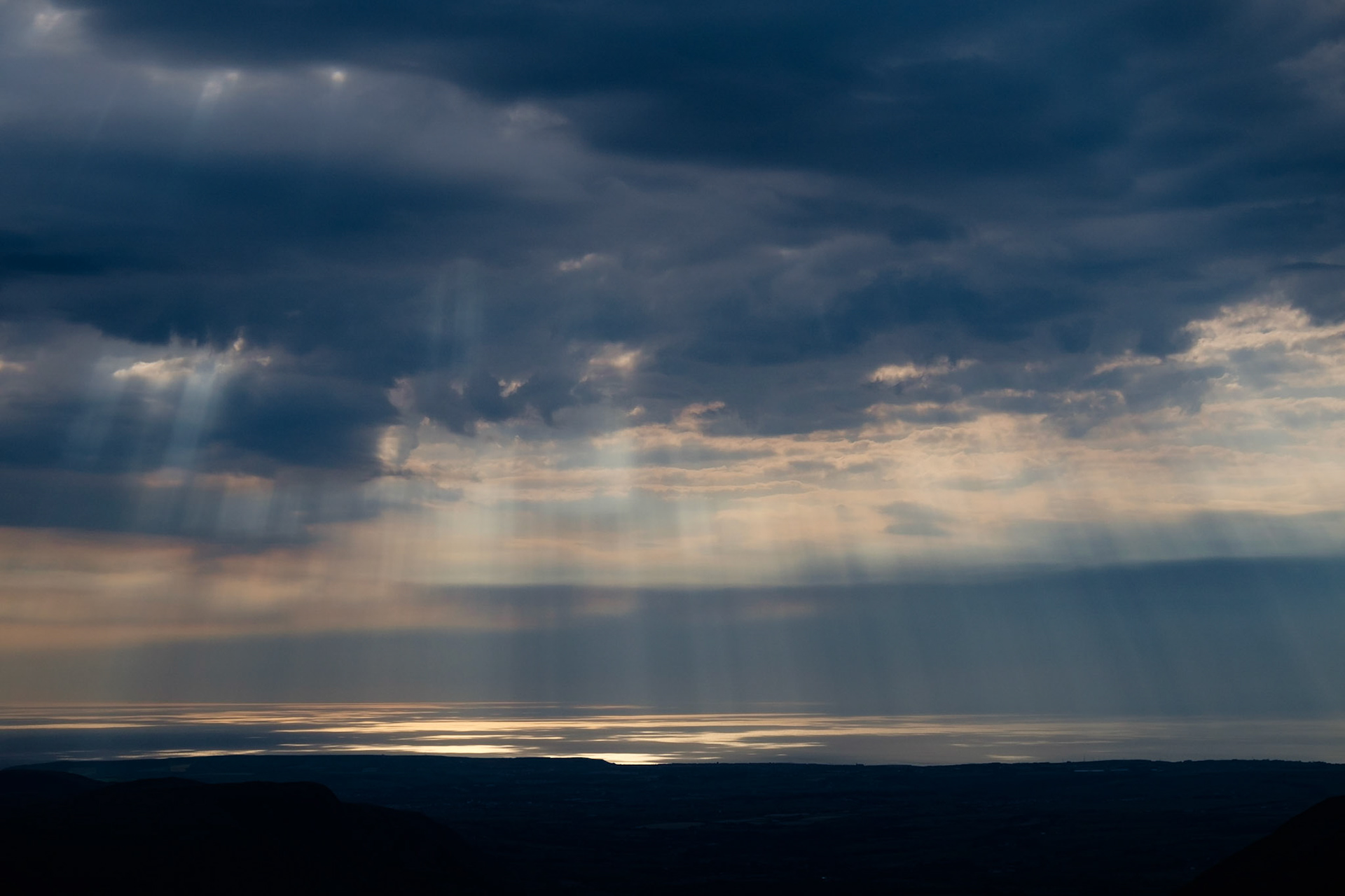 Sunbeams break throught the clouds over the Irish Sea, Lake District National Park, England.