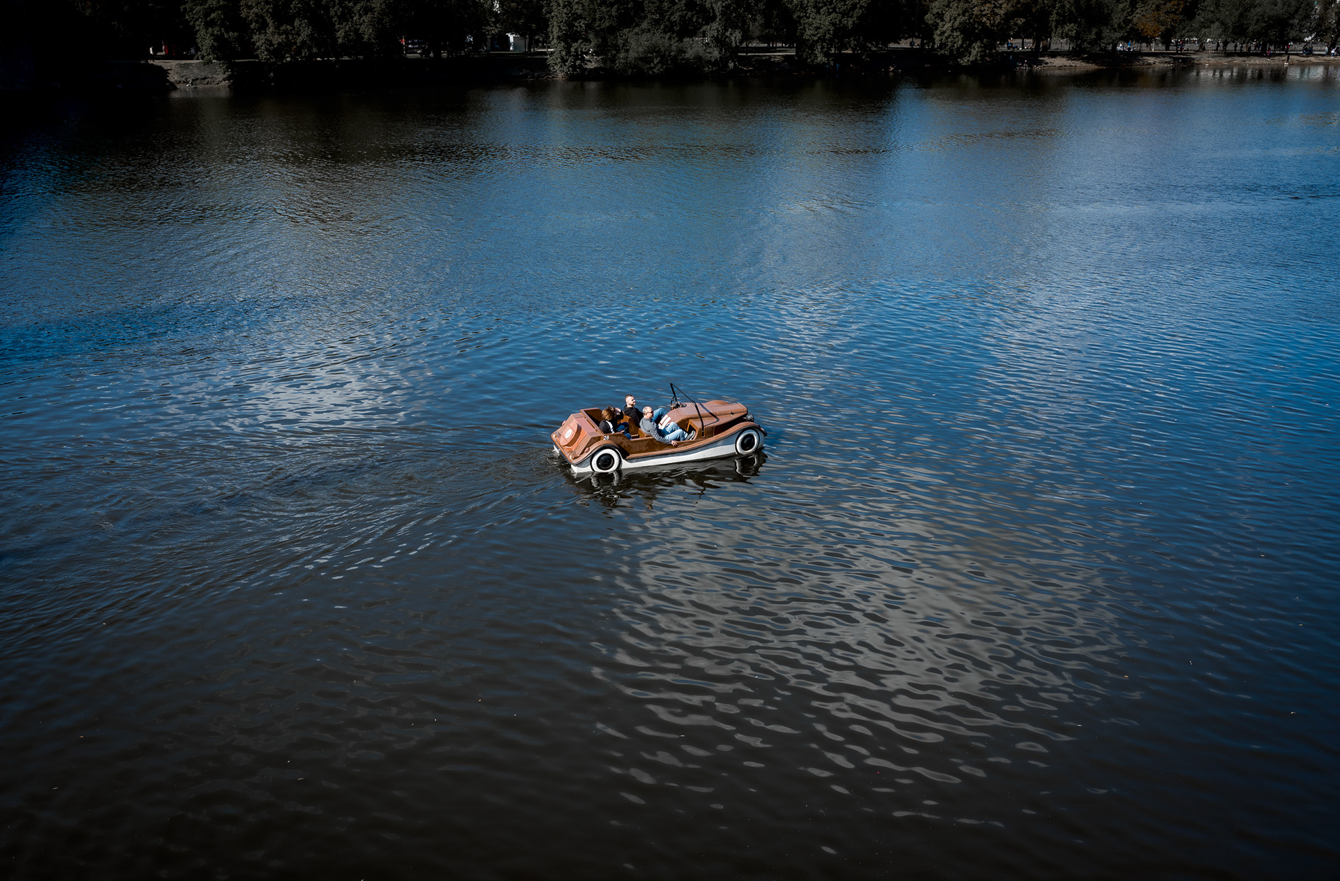 Minimalist high-angle shot of a retro pedal boat drifting on the deep blue Vltava River in Prague.