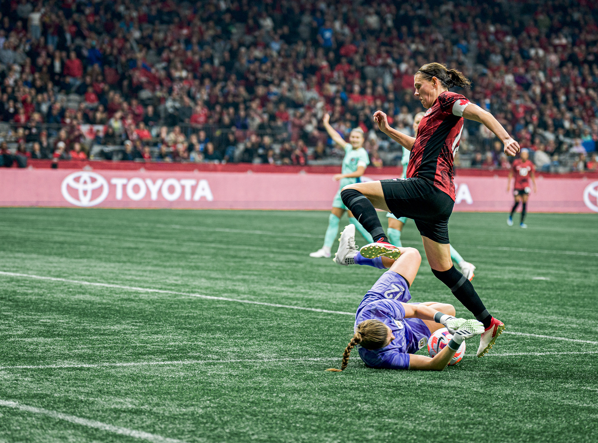 High-speed action photo of Christine Sinclair leaping over the Australian goalkeeper at BC Place.