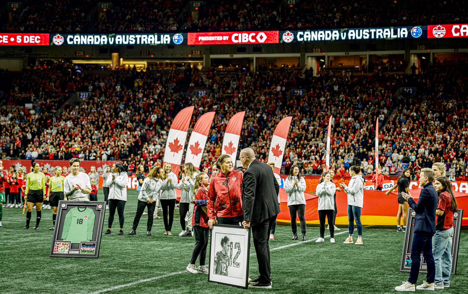 Christine Sinclair receiving a framed artwork during the post-match ceremony.
