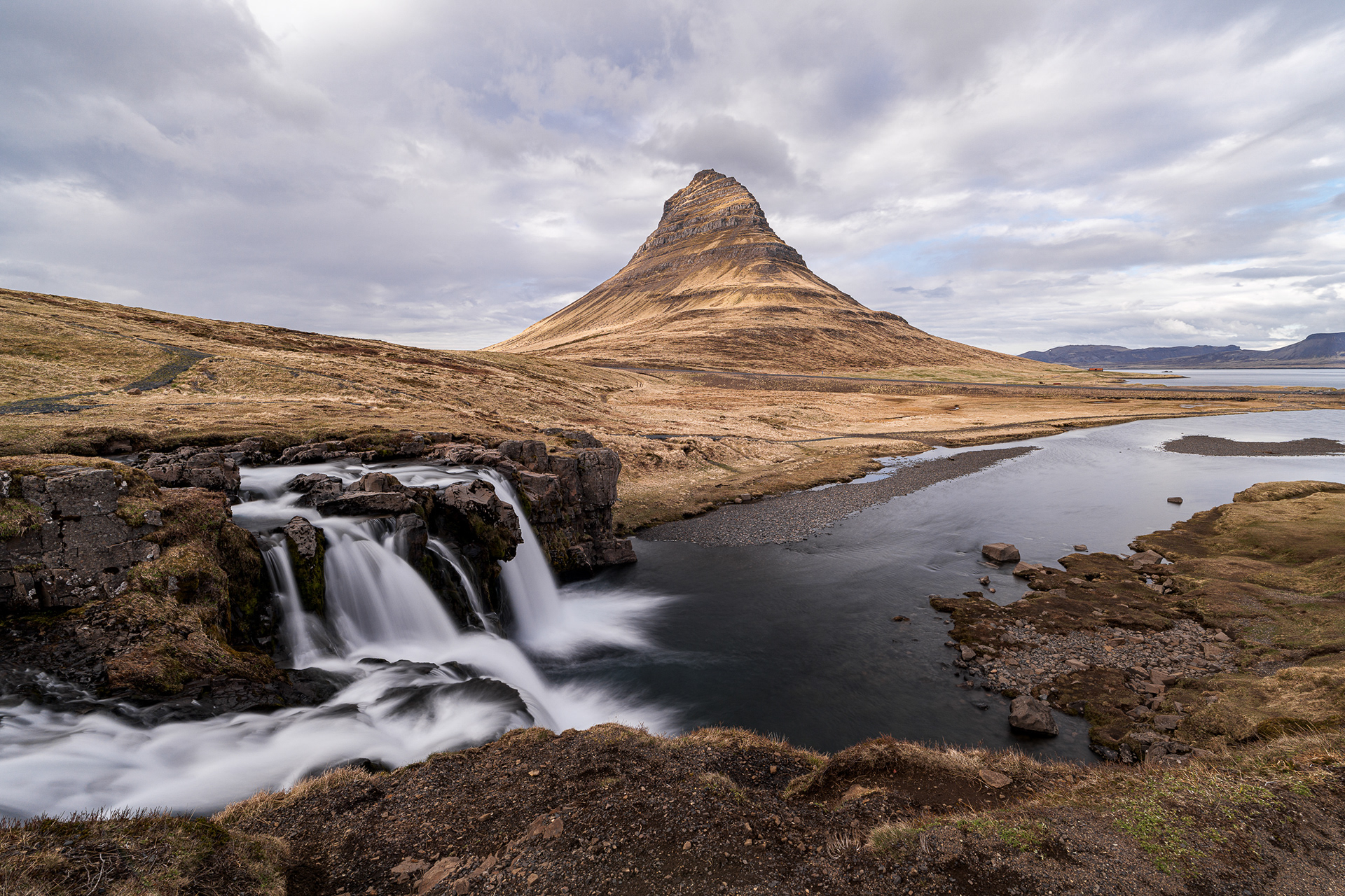 Iconic landscape of the conical Kirkjufell mountain and Kirkjufellsfoss waterfall on the Snaefellsnes Peninsula, Iceland, with a silky water effect.
