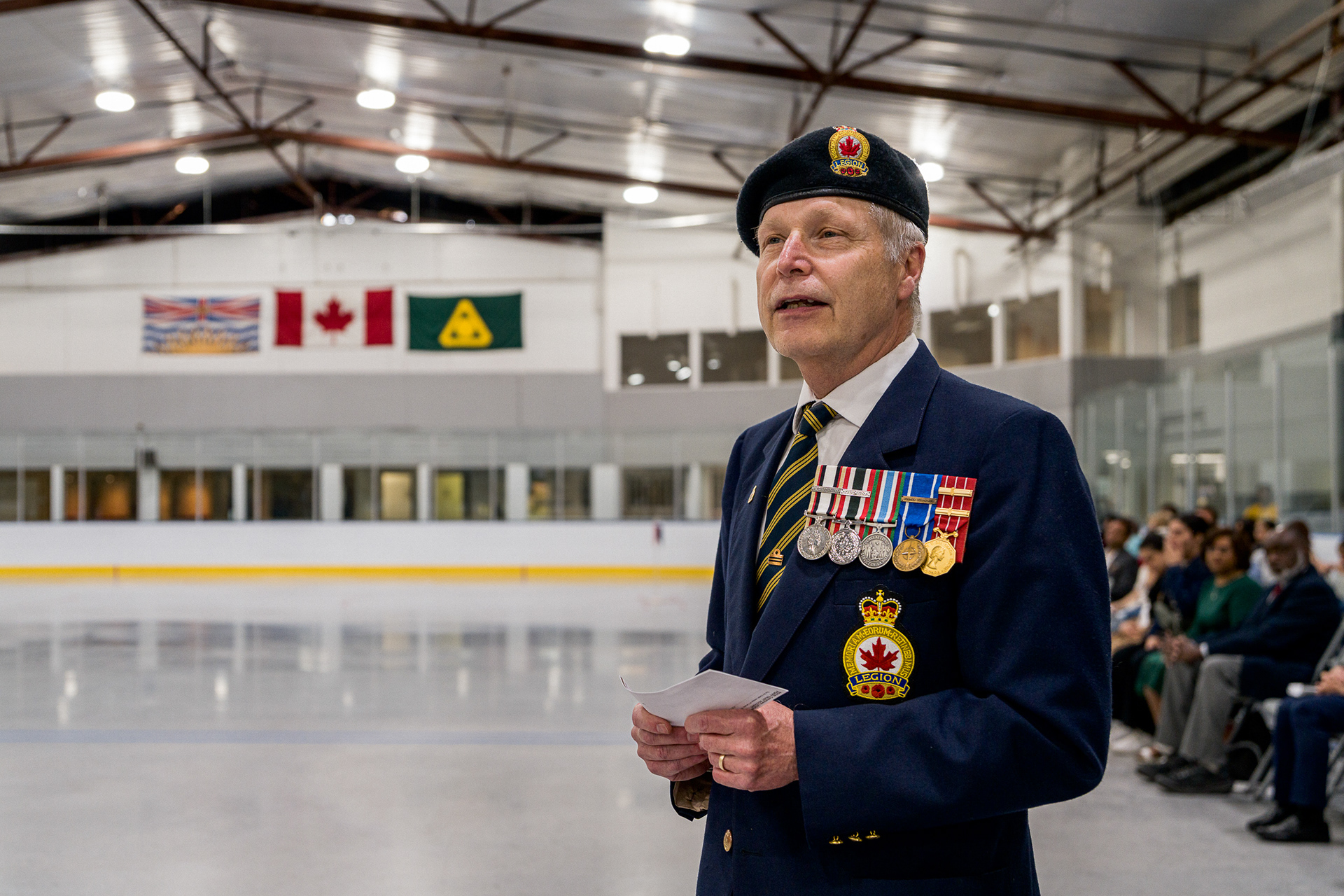Documentary portrait of a Canadian veteran in an in-door ice rink captured on a Sony A1, processed with Cobalt Leica M10r emulation to achieve organic skin tones, deep chromatic density in the navy uniform, and 3D pop.