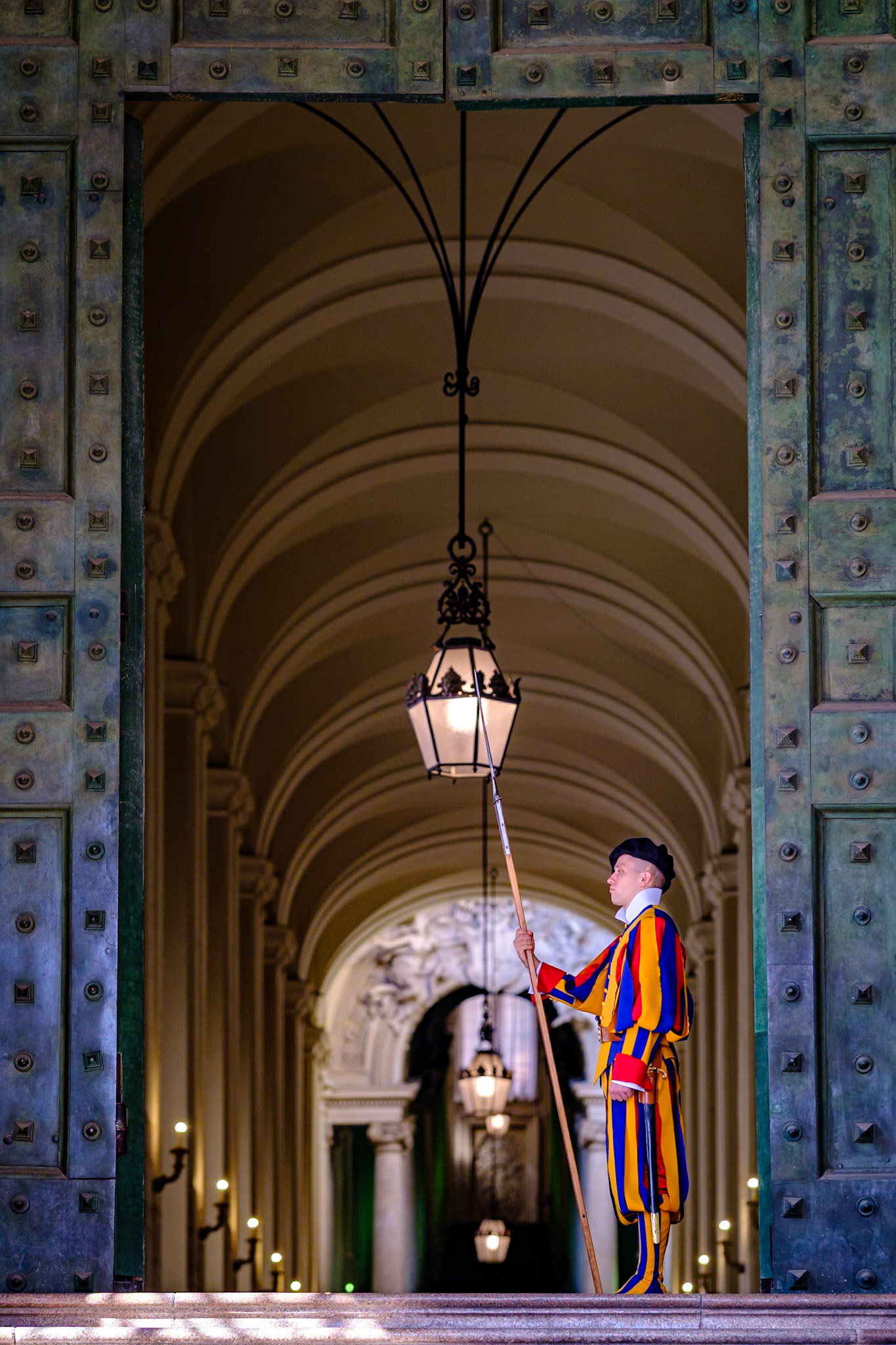 A Swiss guard stands guard at the Bronze Door at the Vatican City, Rome