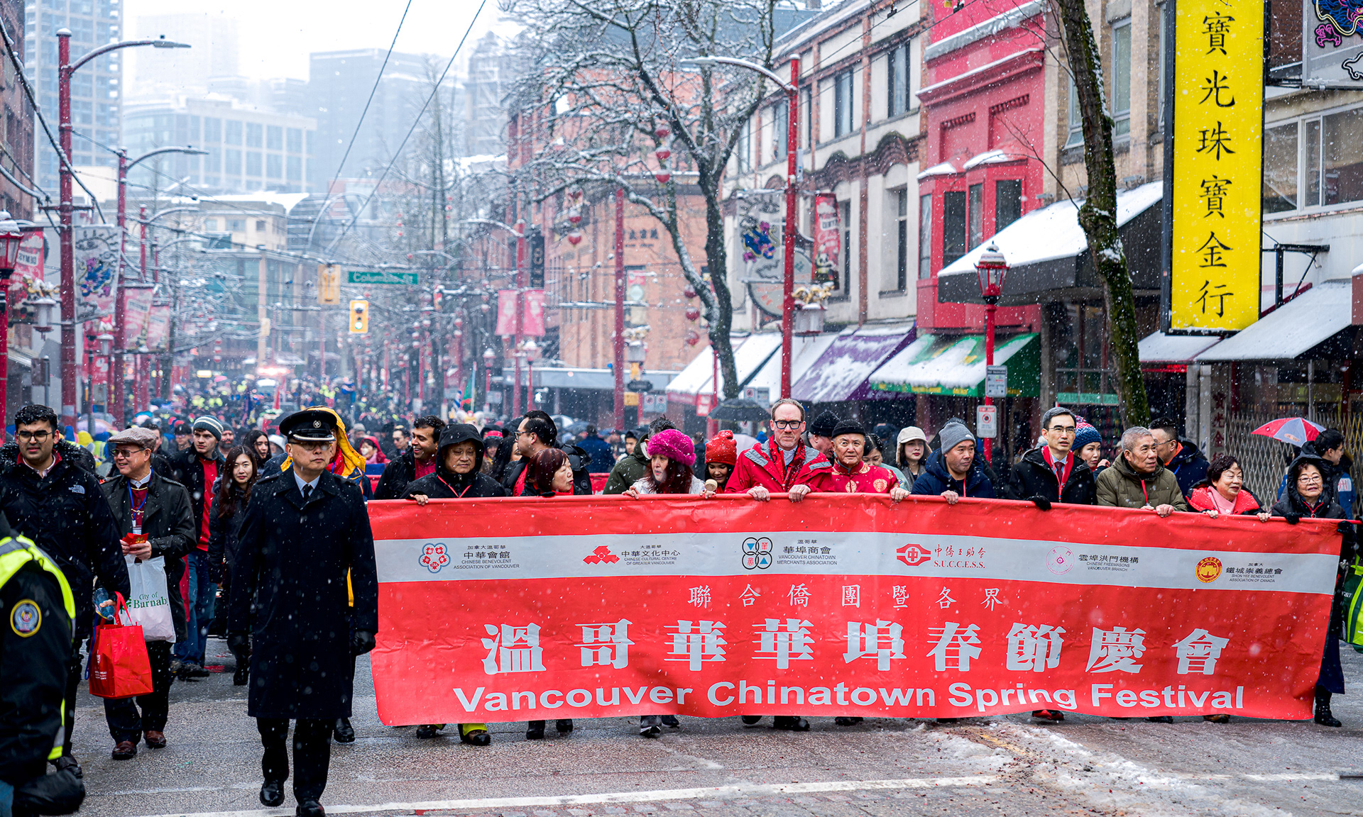 Large red banner in Vancouver Chinatown parade during snowstorm.
