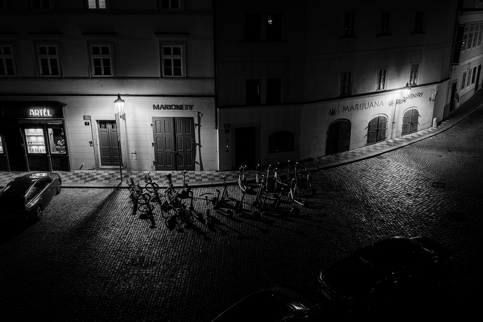A moody, cinematic black and white 15-second long exposure of a Prague street corner, captured on a Sony A7 IV and processed with Leica Monochrom CCD emulation for inky shadows.