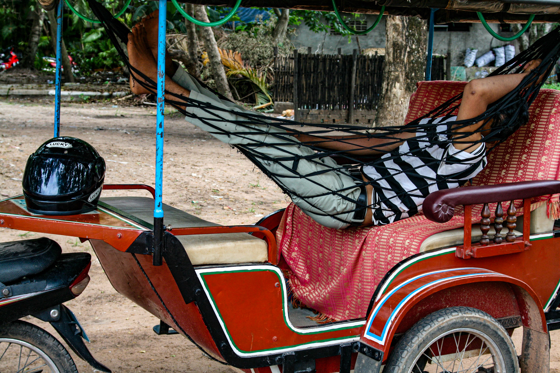 Tuk-tuk driver takes a nap while waiting for the next fare.